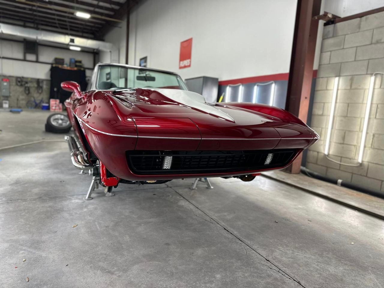 A red corvette is parked in a garage.