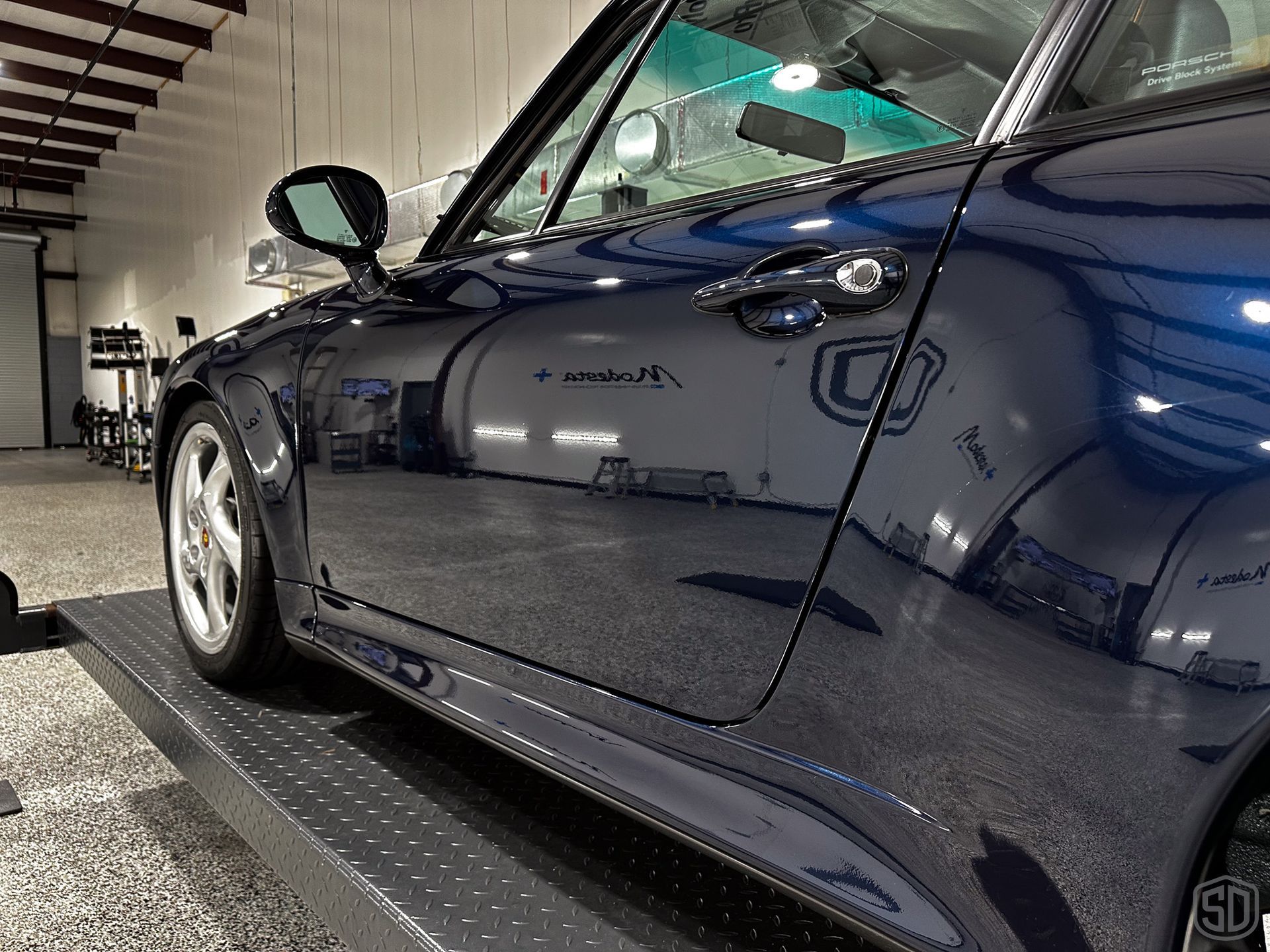 A blue car is parked in a garage with the door open