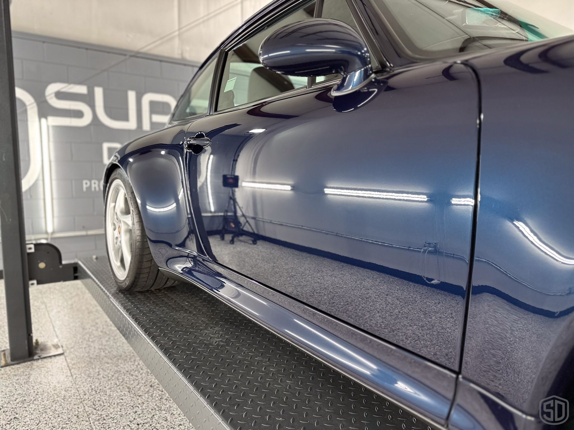 A blue sports car is parked on a lift in a garage.