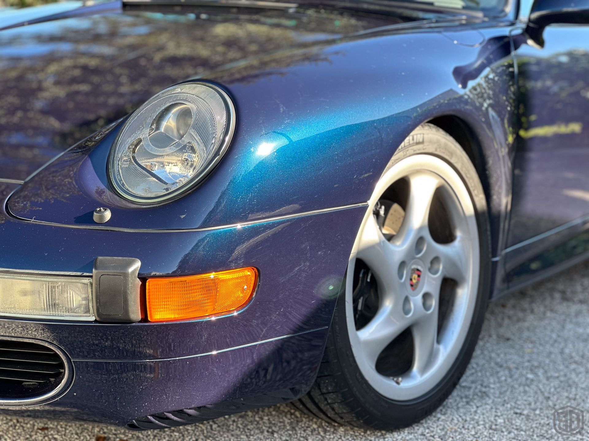 A purple porsche is parked in a parking lot