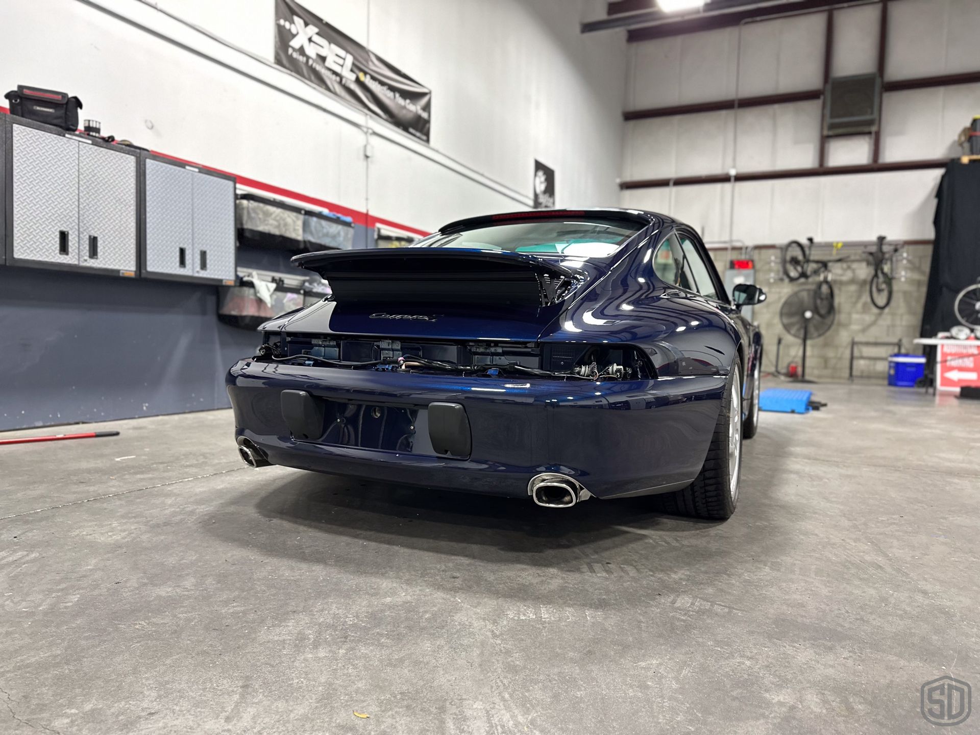 A blue porsche 911 turbo is parked in a garage.