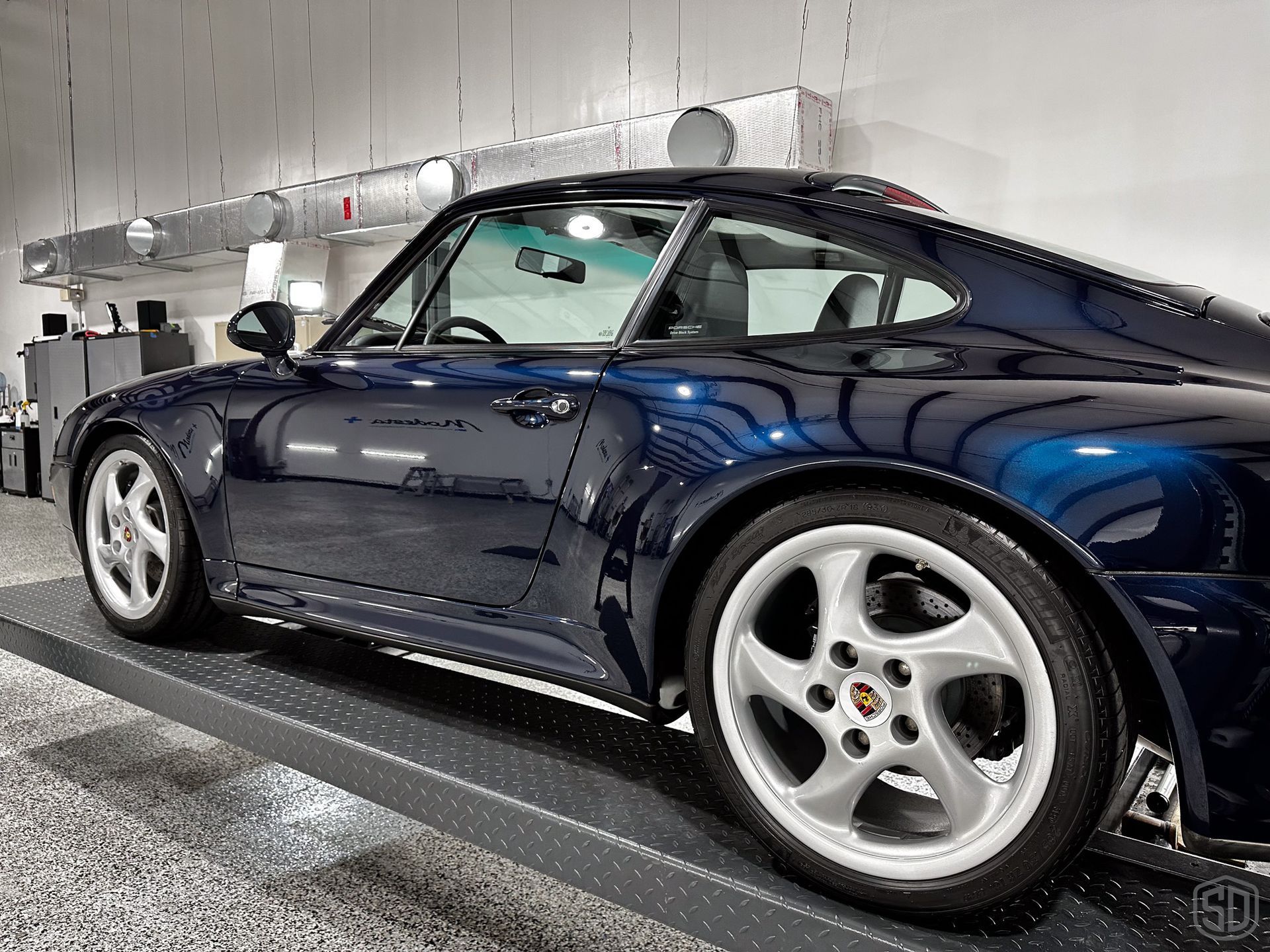A blue sports car is parked in a garage