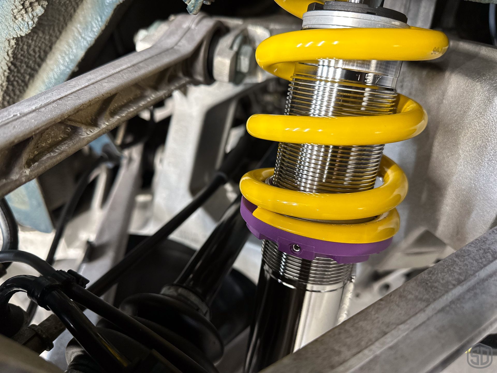 A close up of a yellow and purple shock absorber on a car.