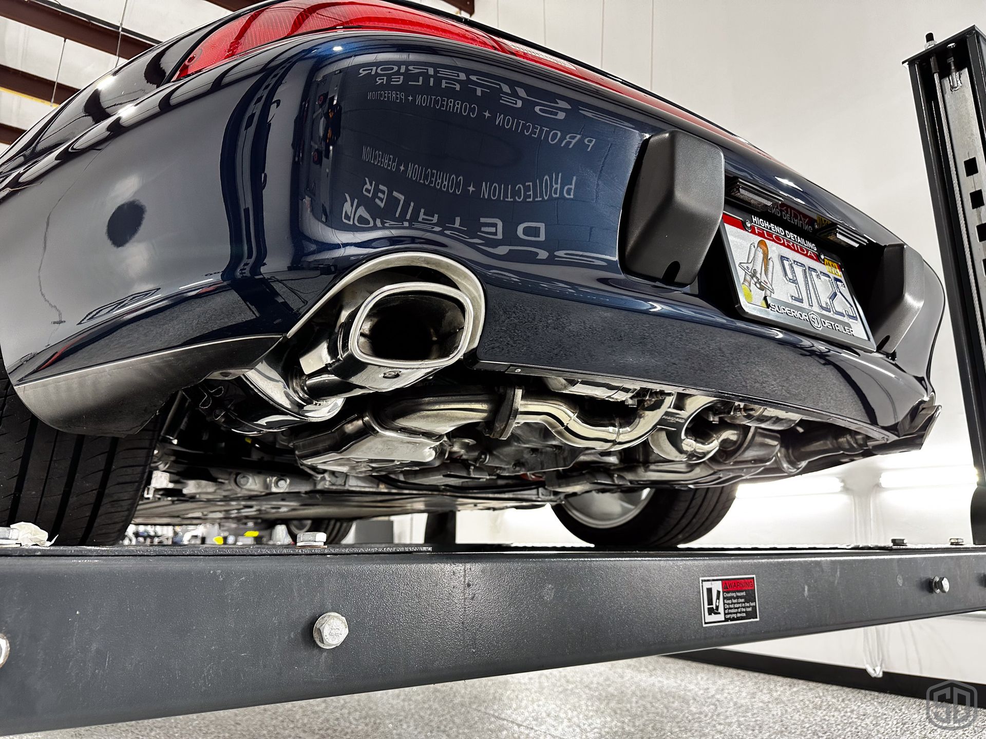 A car with a new jersey license plate is on a lift
