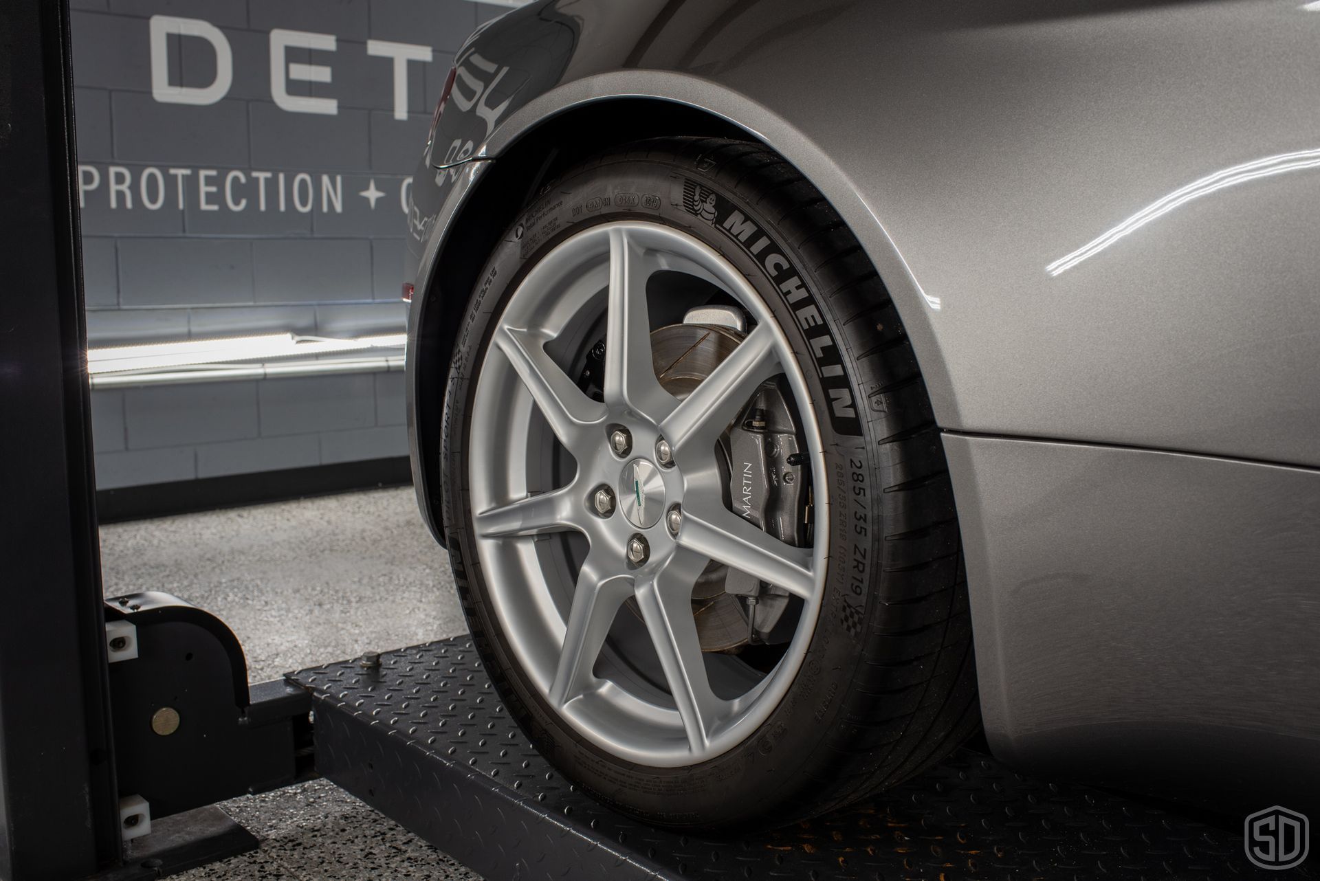 A car is sitting on a lift with a michelin tire on it.