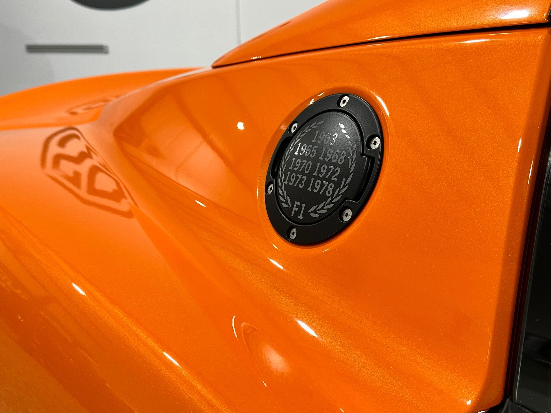 A close up of an orange car with a black fuel cap