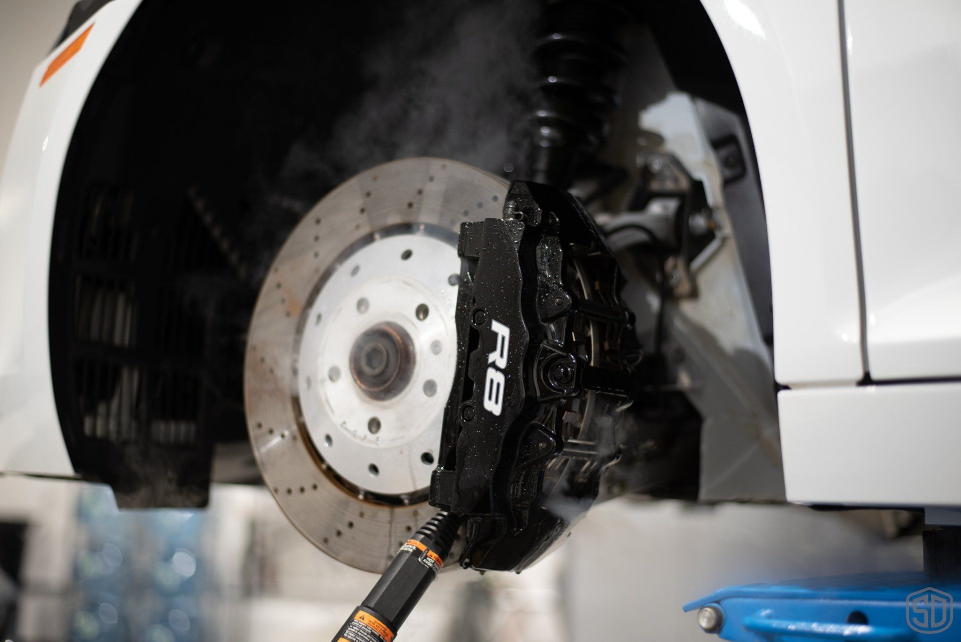 A close up of a car 's brake system on a lift.