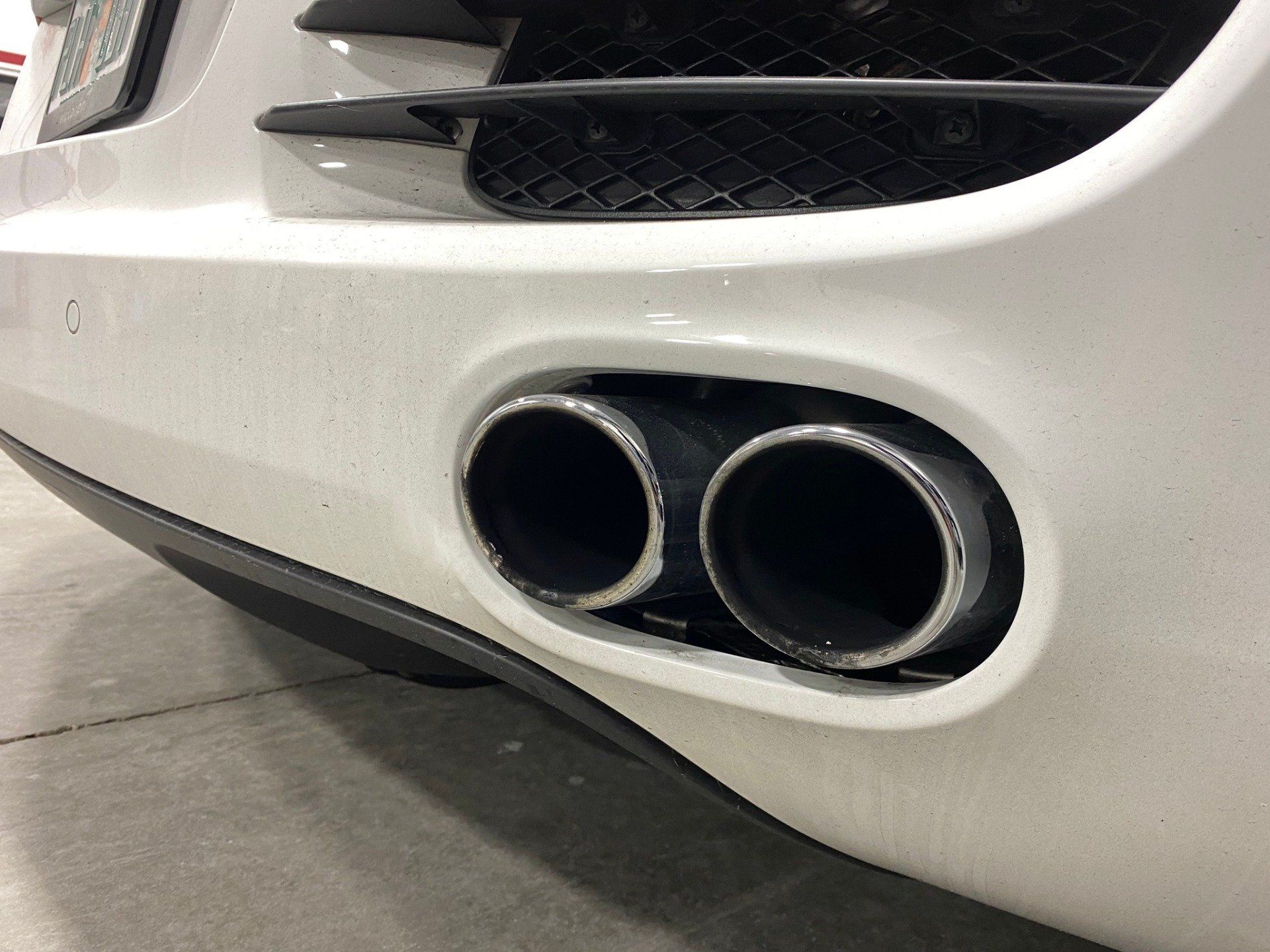 A close up of a white car 's exhaust pipes