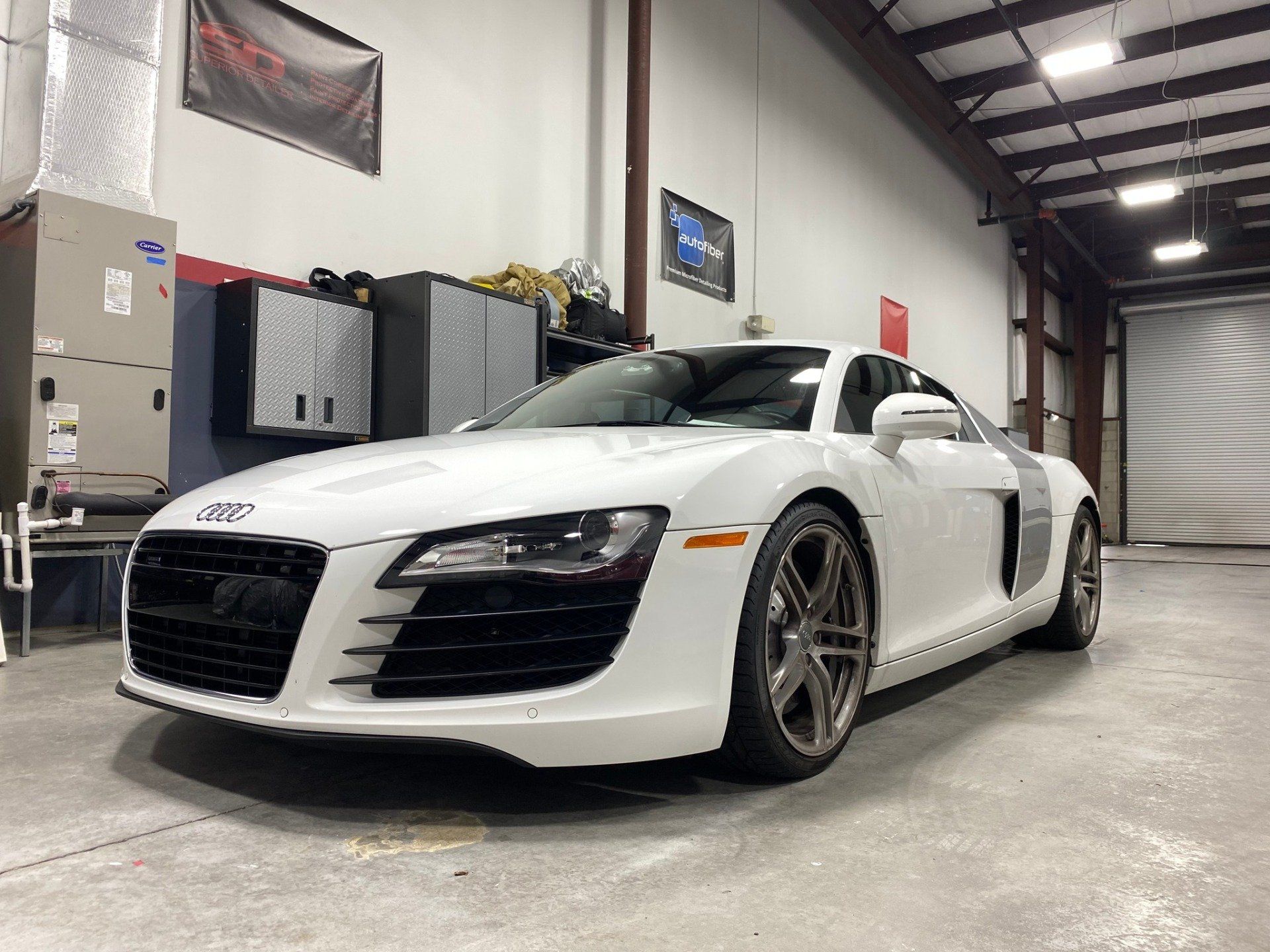 A white audi r8 is parked in a garage.