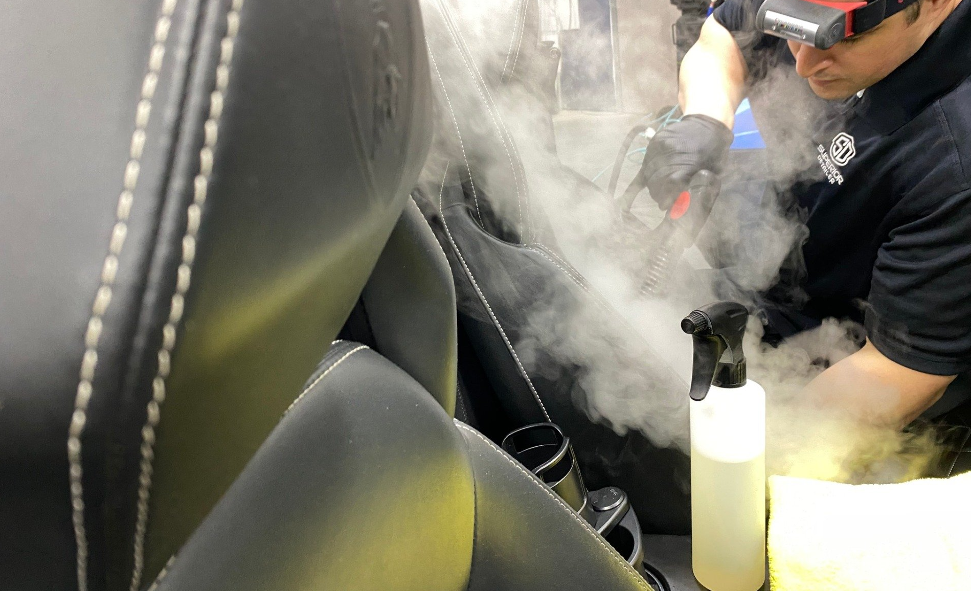 A man is cleaning a car seat with a spray bottle.