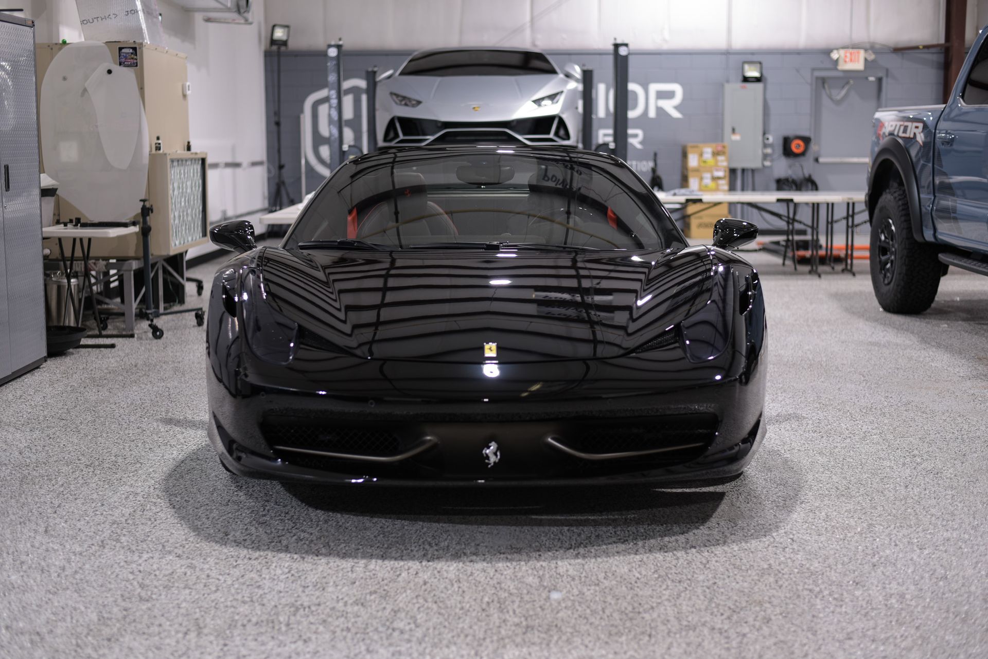 A black ferrari sports car is parked in a garage.