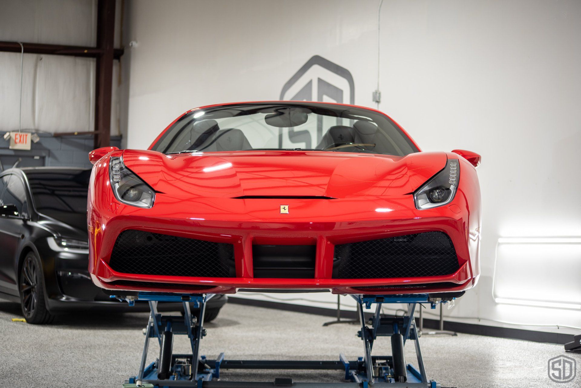 A red ferrari is sitting on a lift in a garage.