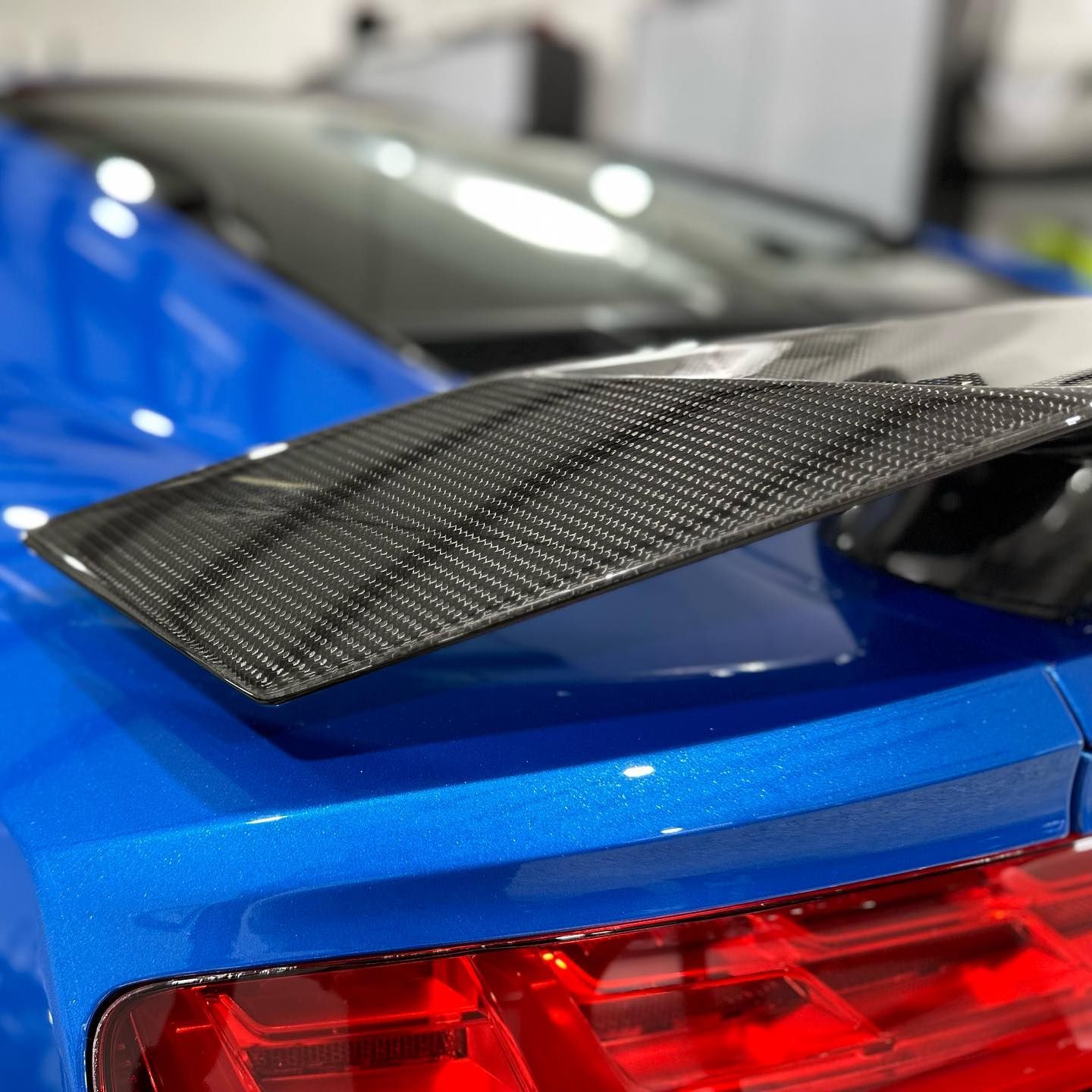 A close up of a blue car with a carbon fiber spoiler