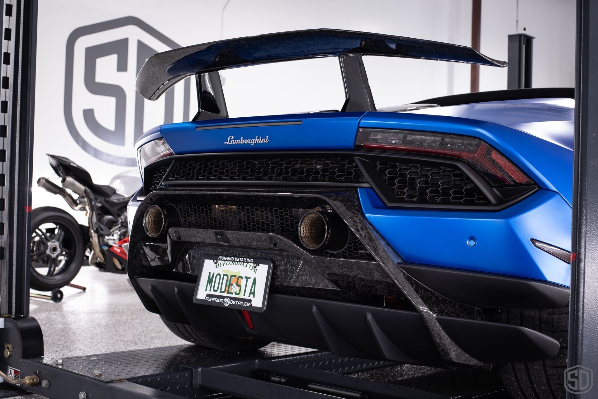 A blue lamborghini is on a lift in a garage.