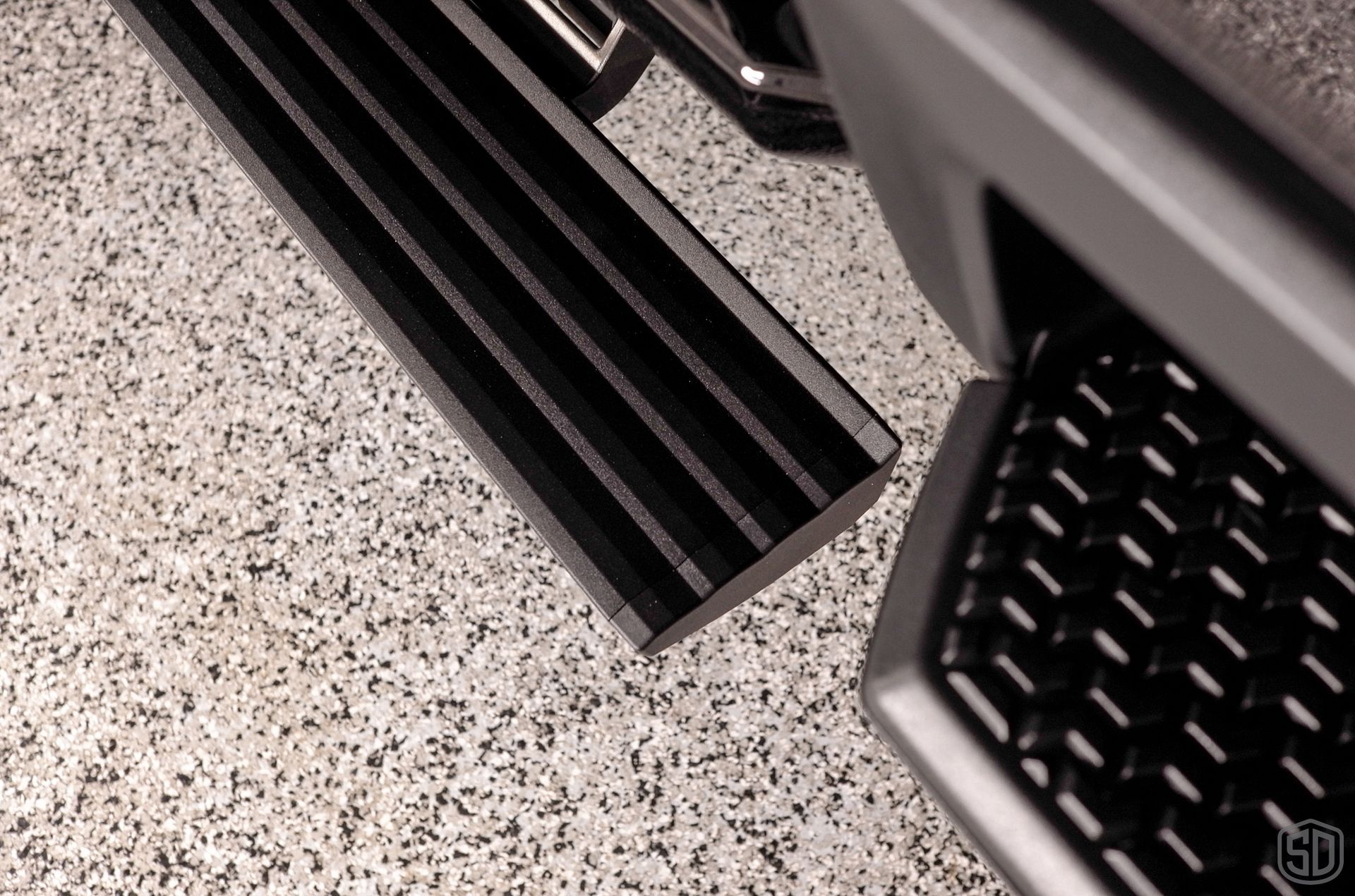 A close up of a car 's side step on a concrete floor.