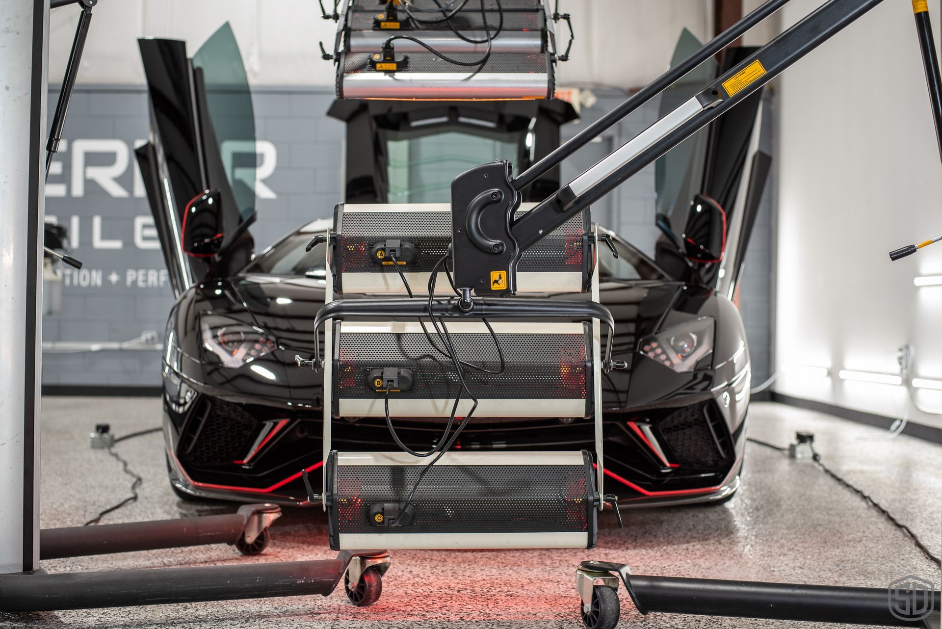 A black sports car is sitting on top of a cart in a garage.