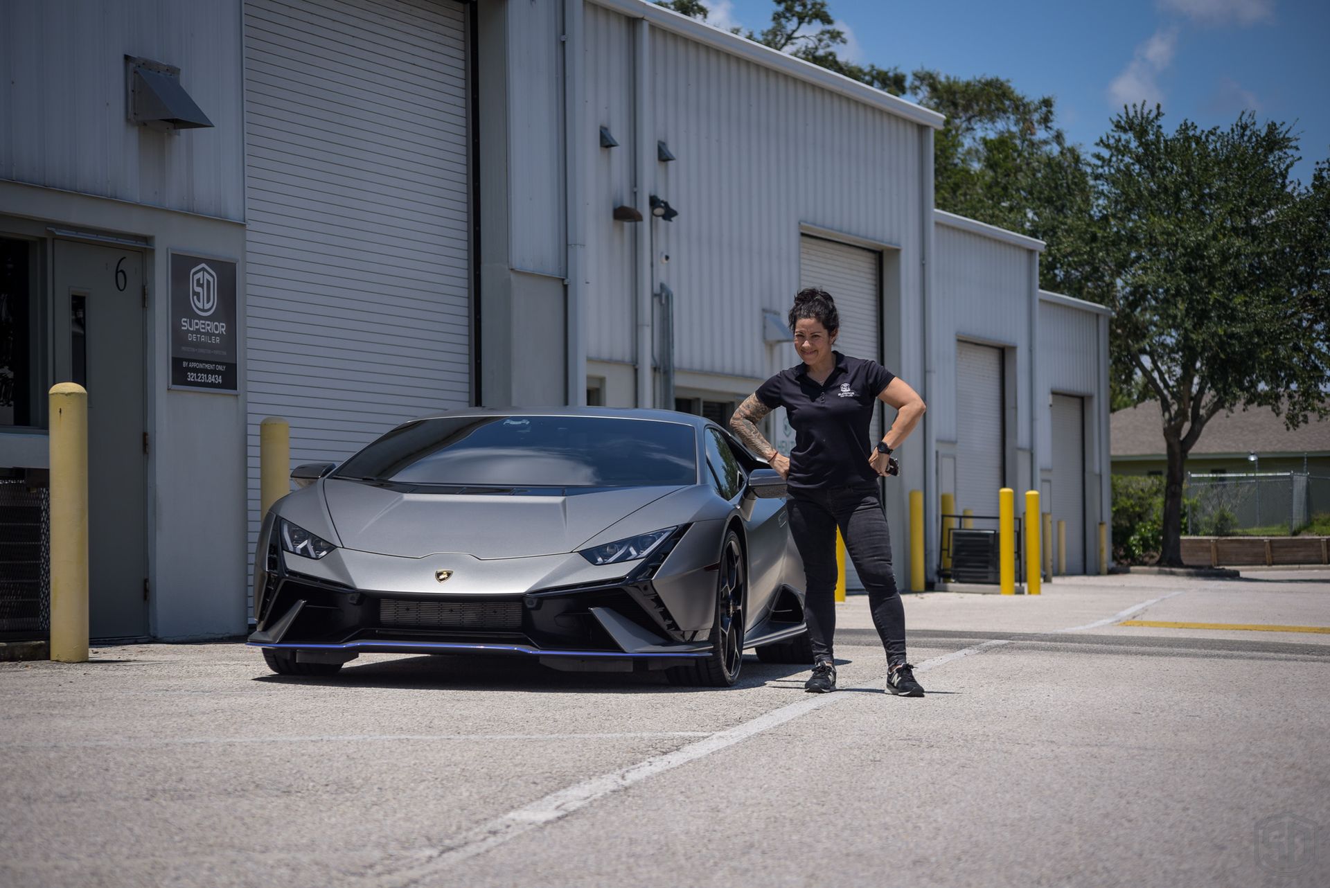 A woman is standing next to a lamborghini in a parking lot.