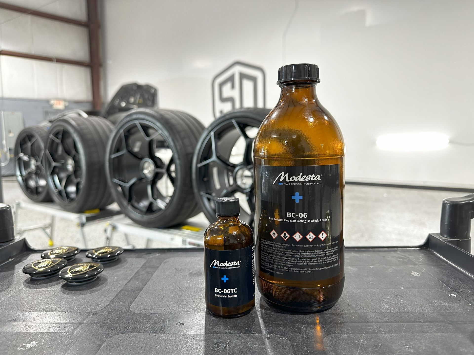 Two bottles of liquid are sitting on a table in a garage.