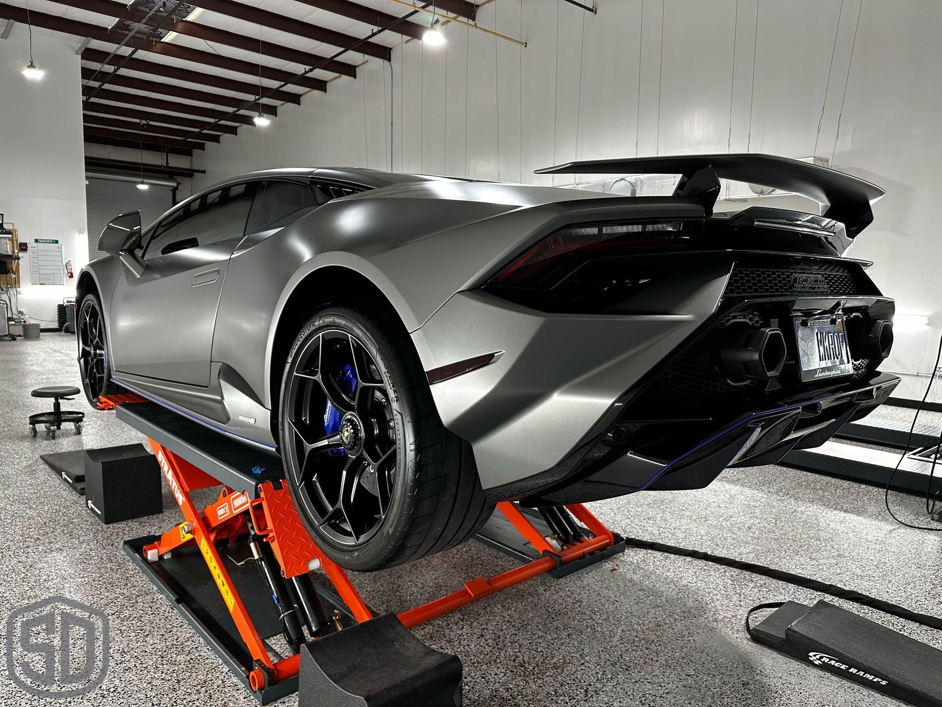 A lamborghini huracan is sitting on a lift in a garage.