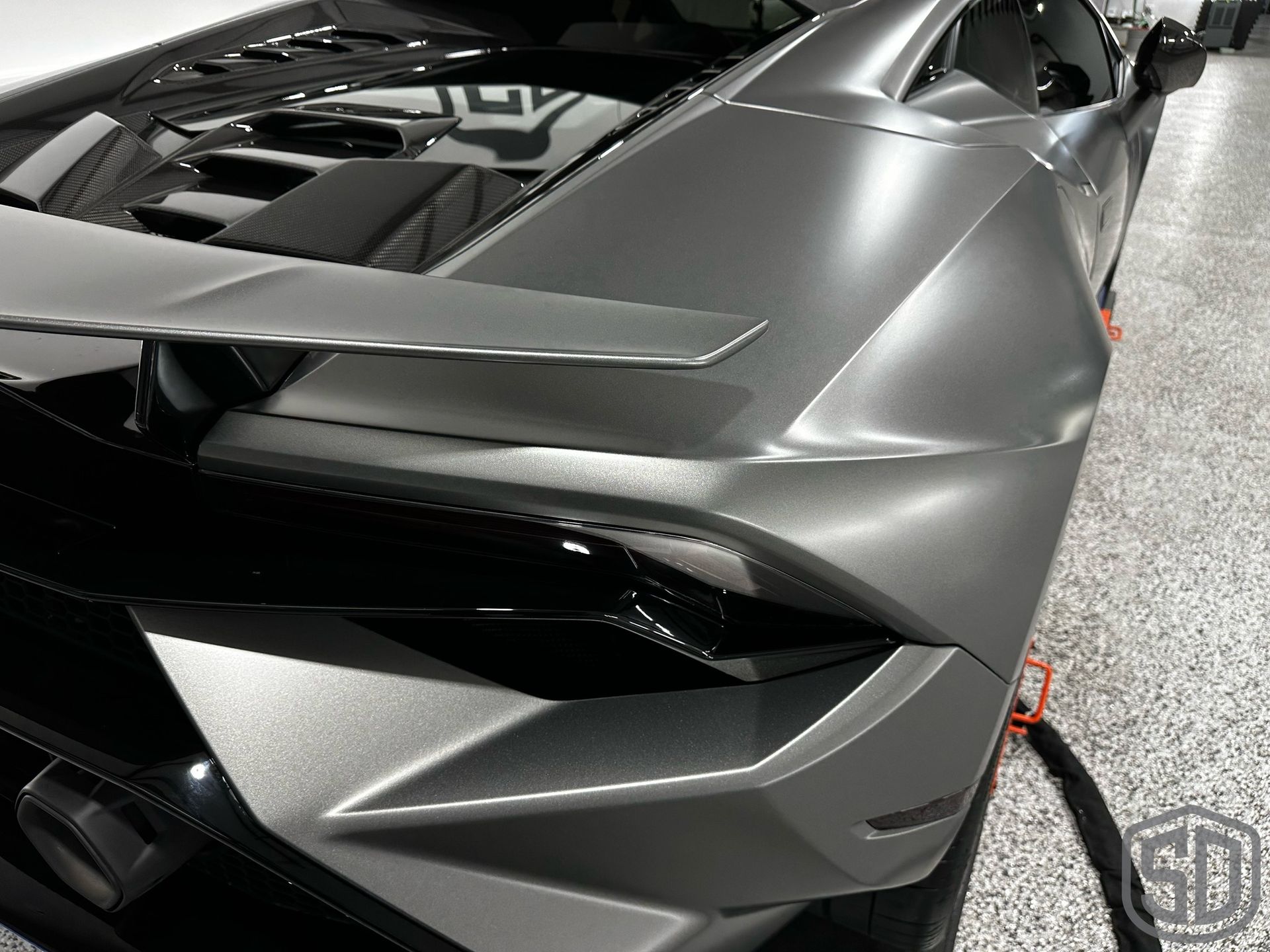 A gray and black sports car is parked in a garage