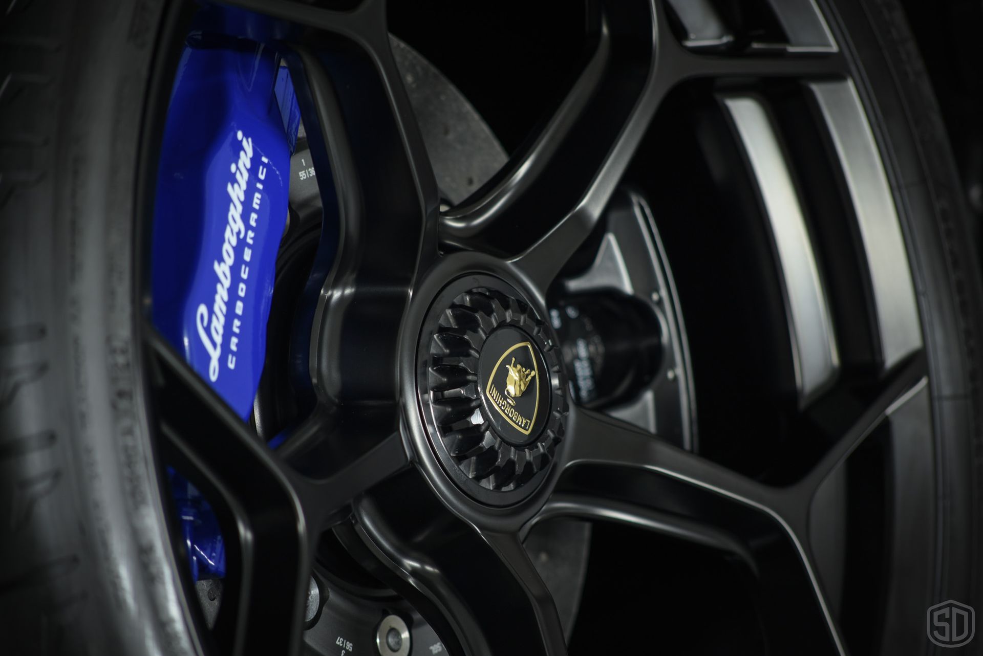 A close up of a lamborghini wheel with a blue brake caliper.