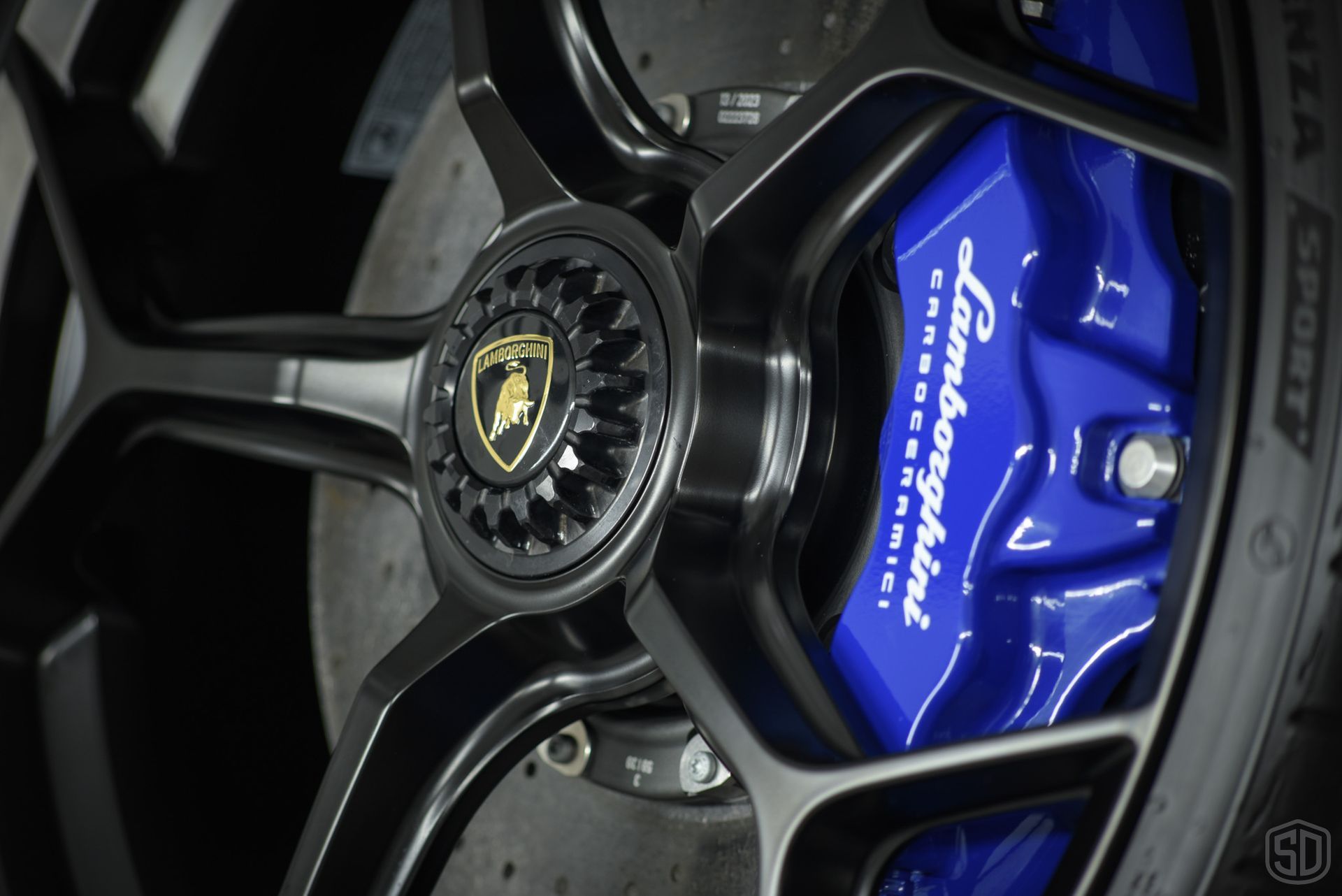 A close up of a lamborghini wheel with a blue brake caliper