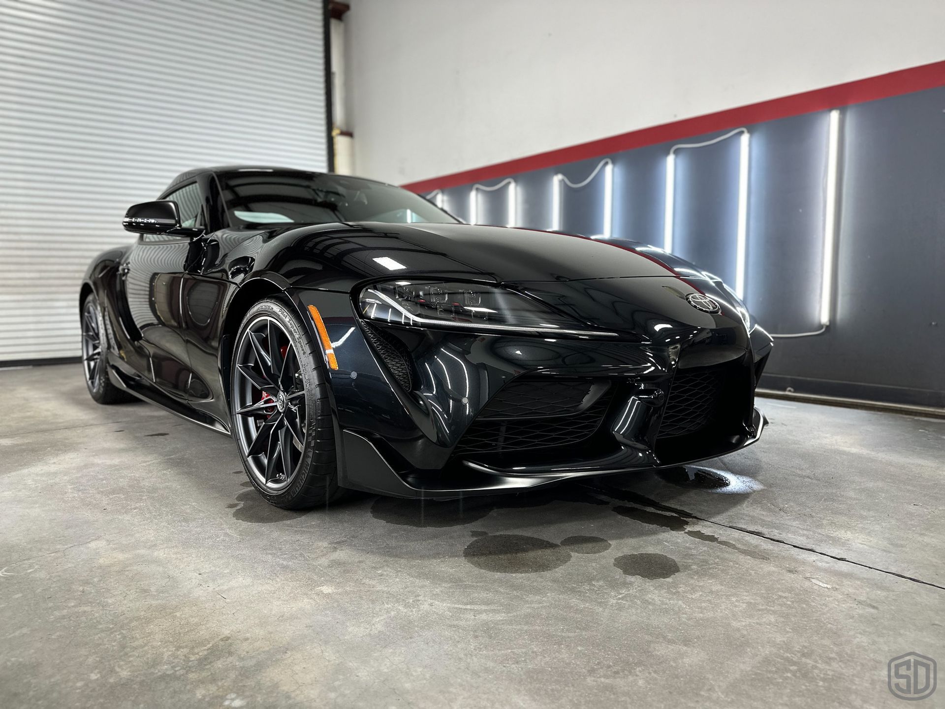 A black toyota supra is parked in a garage.