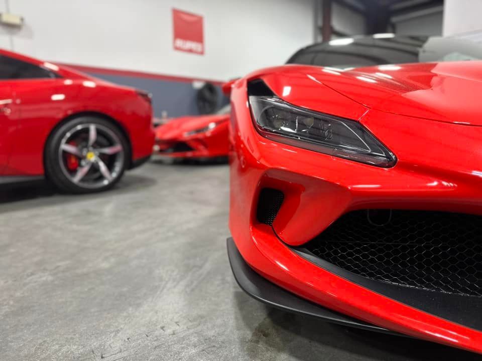 Two red sports cars are parked in a garage.