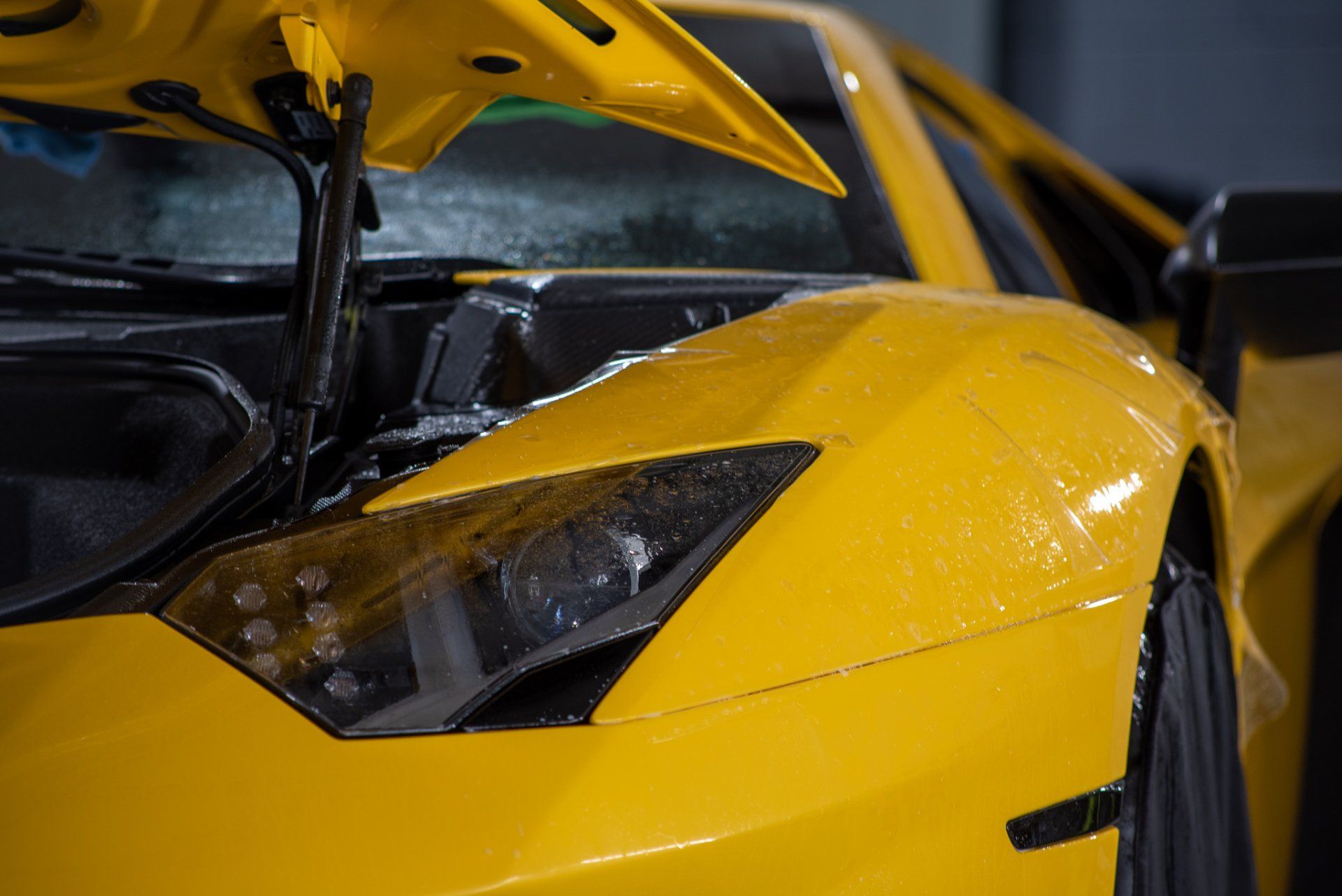 A close up of a yellow sports car with the hood open.