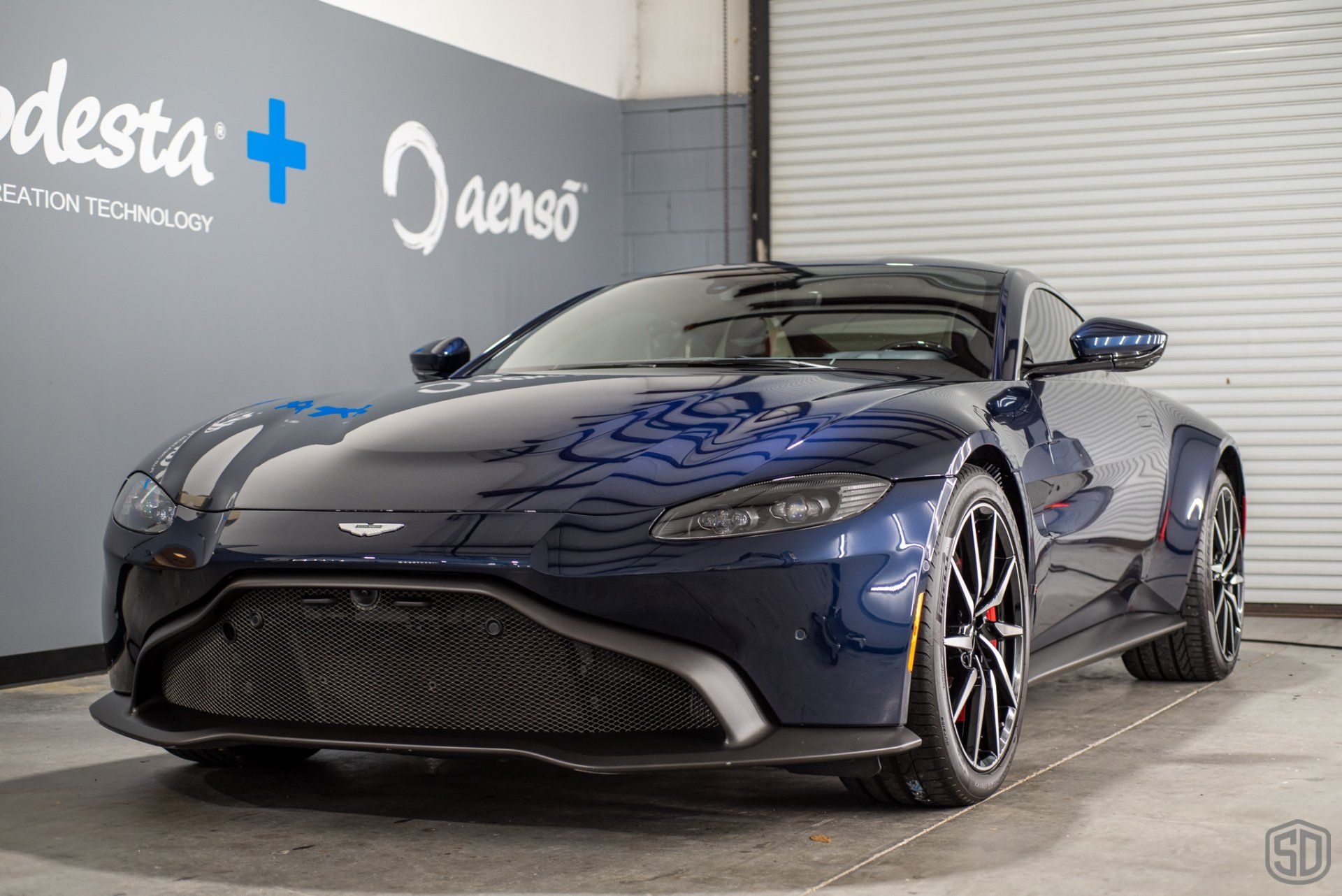 A blue aston martin vantage is parked in a garage.