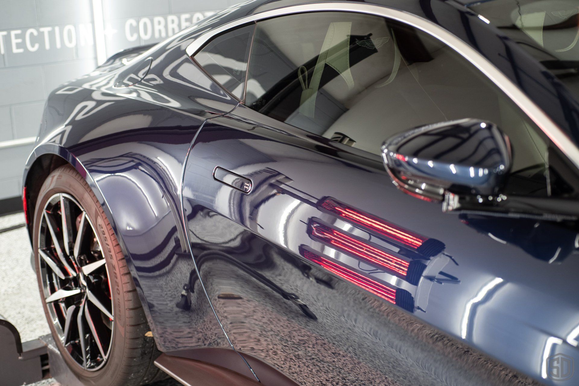 A blue sports car is parked in front of a building that says ' tection correc ' on it