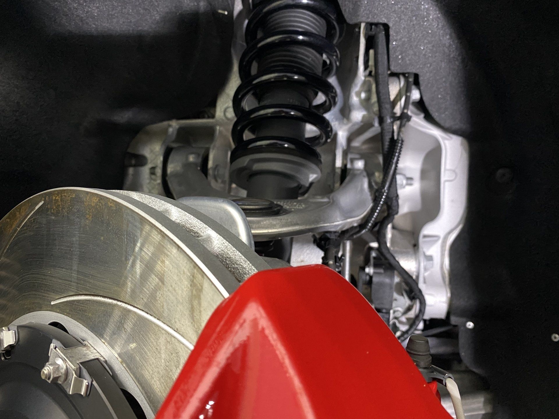A close up of a car suspension with a red brake caliper