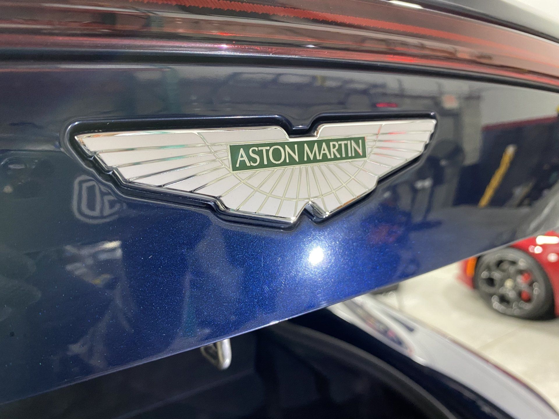 The trunk of a blue aston martin car is open.