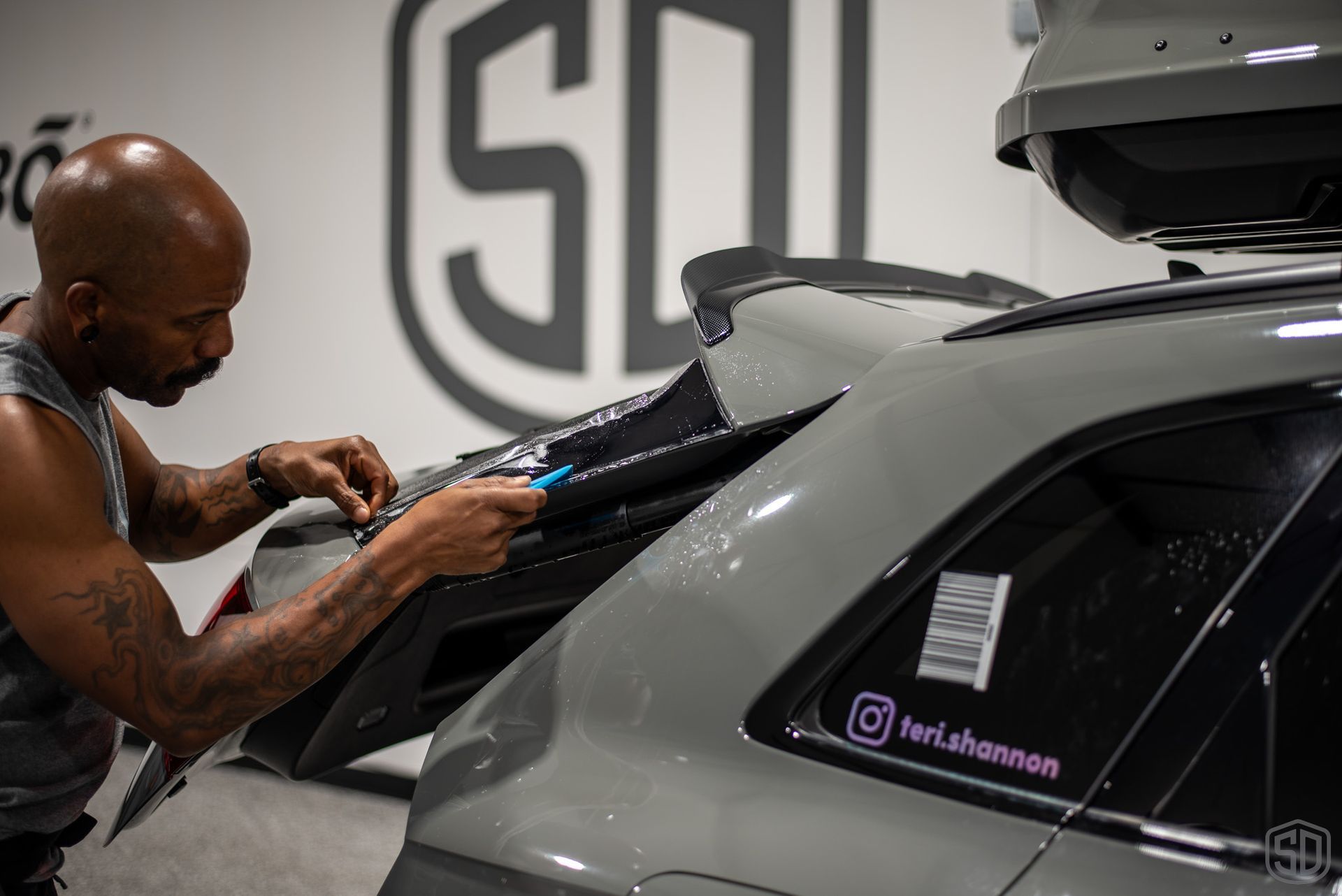 A man is wrapping a car with a sticker on it.