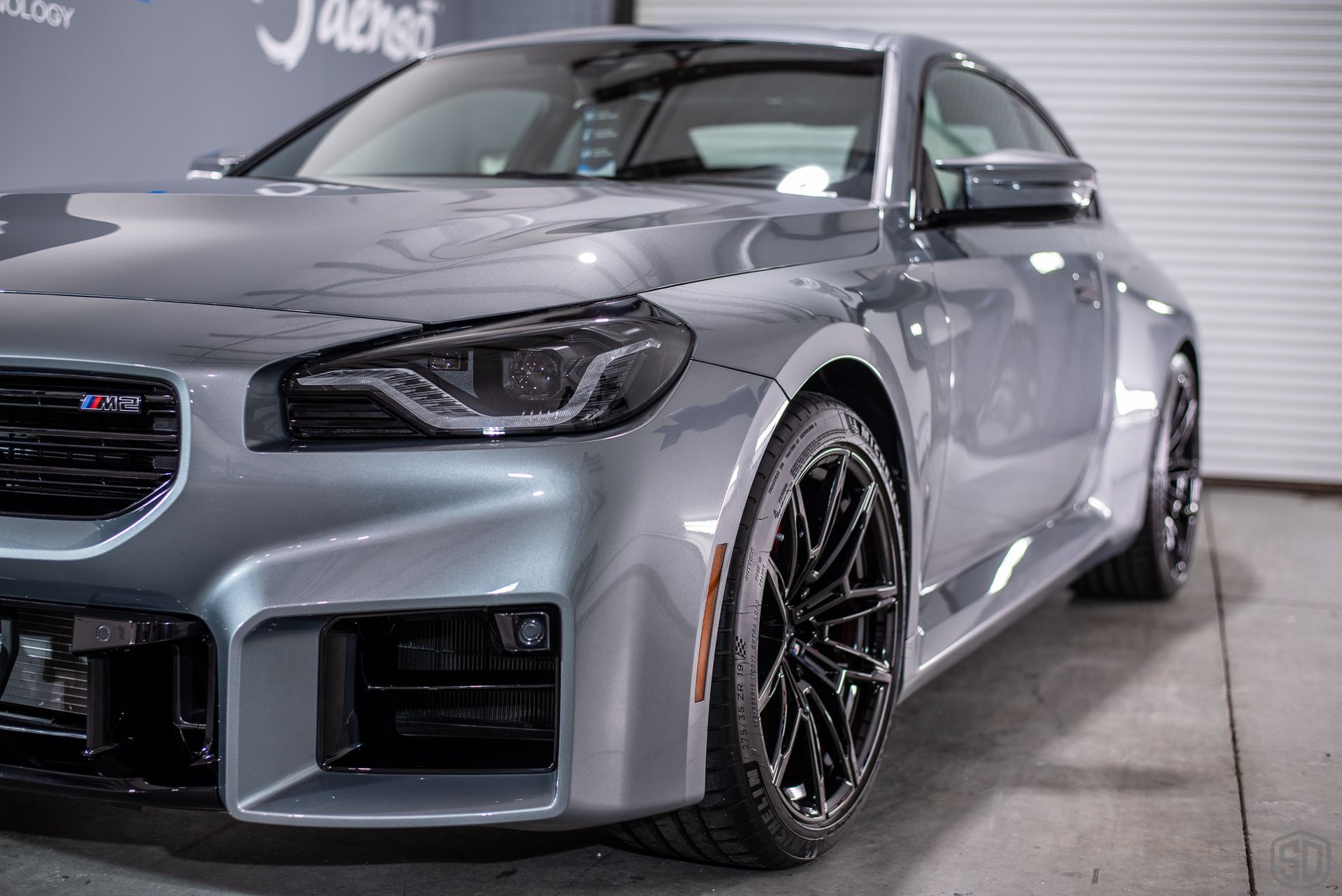 Gray BMW M2 parked in a garage setting.