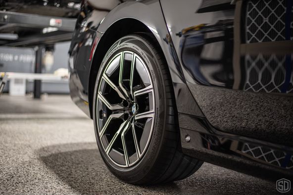 A close up of a car 's wheel and tire in a parking lot.