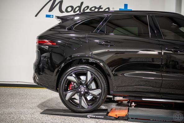 A black car is sitting on a lift in a garage.