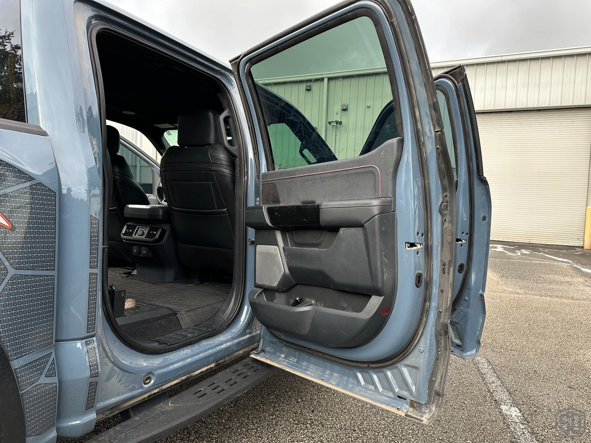 A truck with its doors open is parked in a parking lot.