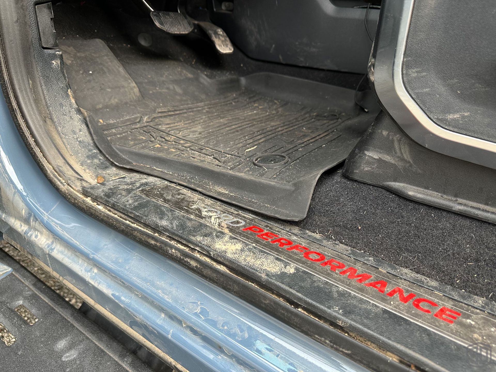 A dirty car door with a performance sticker on it