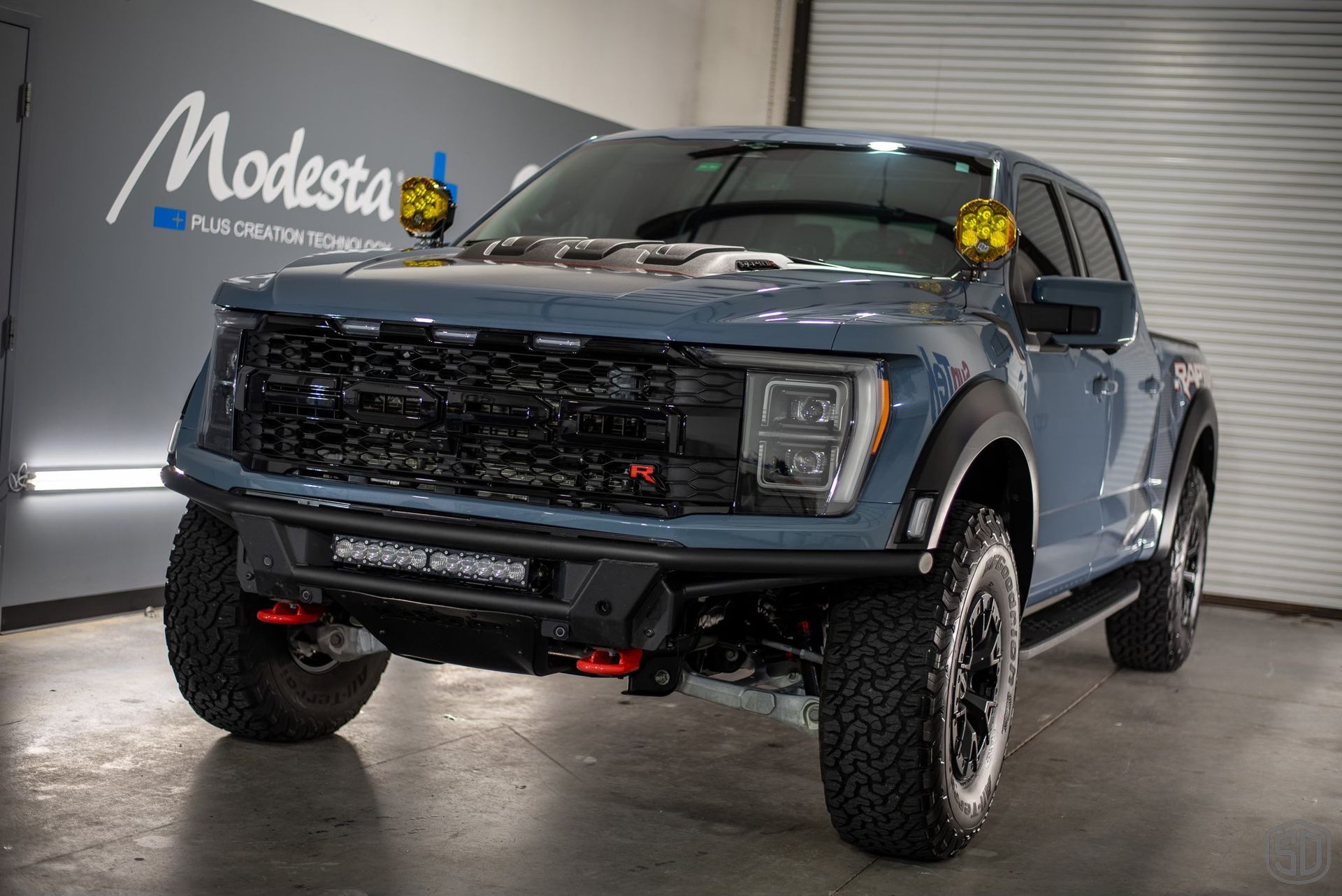 A blue pickup truck is parked in front of a garage door.