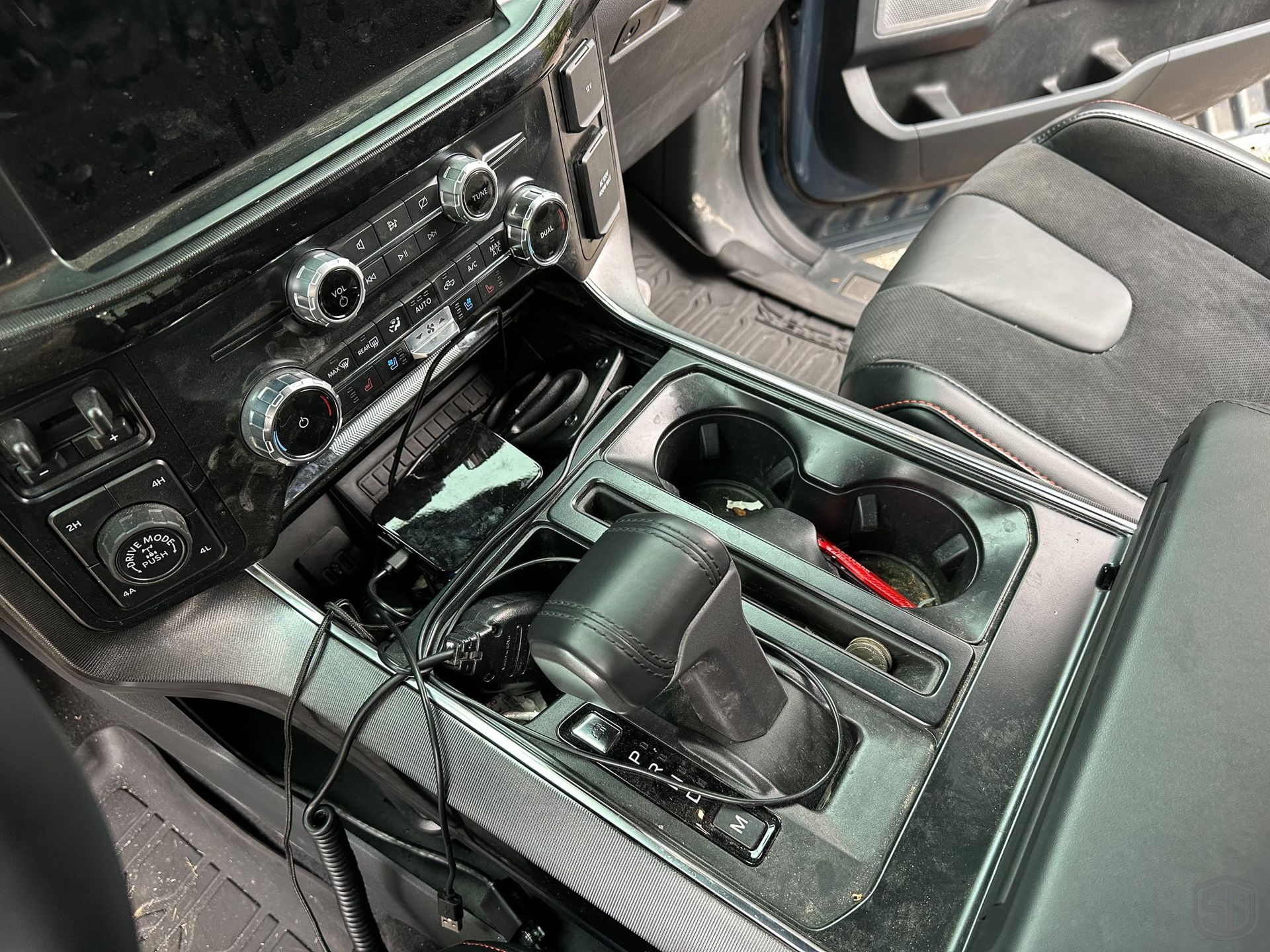 The center console of a car with a charger in it.