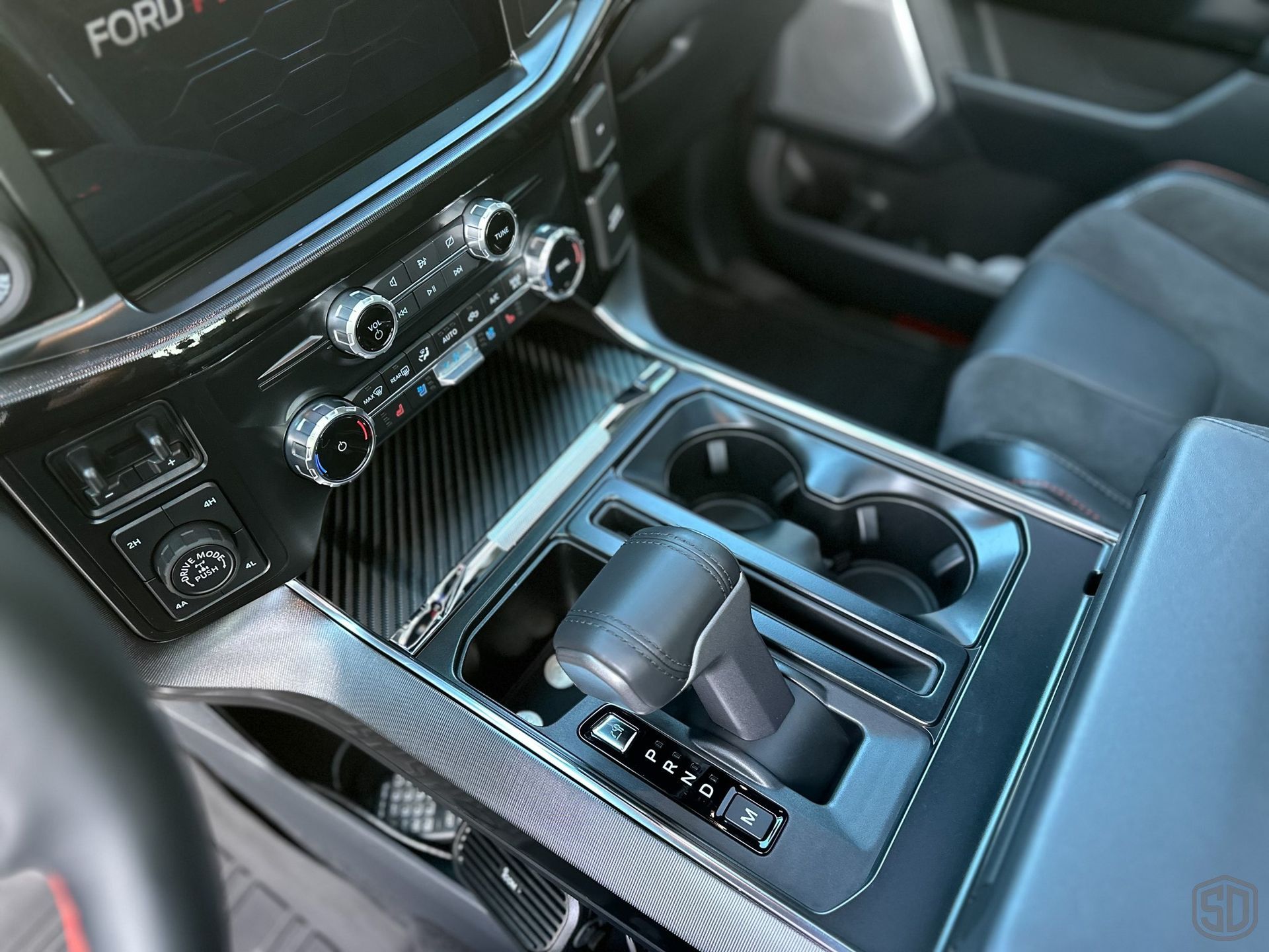 The interior of a ford truck with a shifter and cup holders