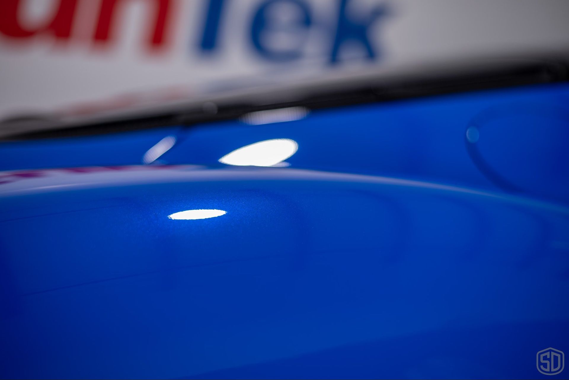 A blue car is parked in front of a sign that says quick