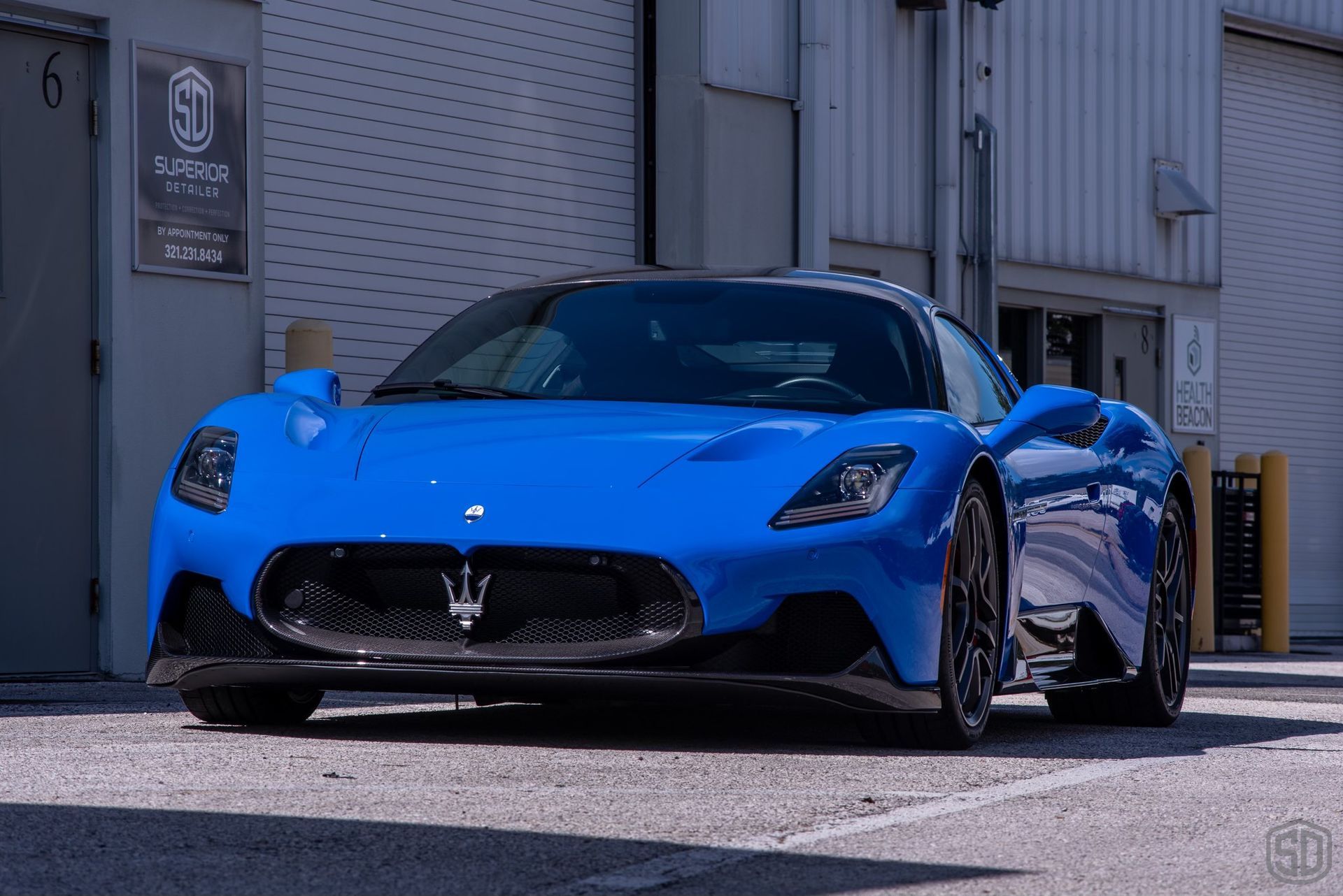 A blue sports car is parked in front of a building.