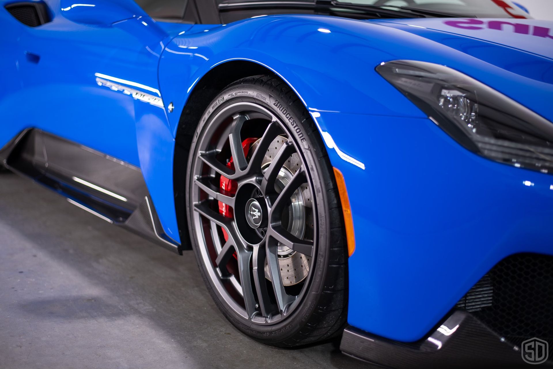 A close up of a blue sports car with black wheels