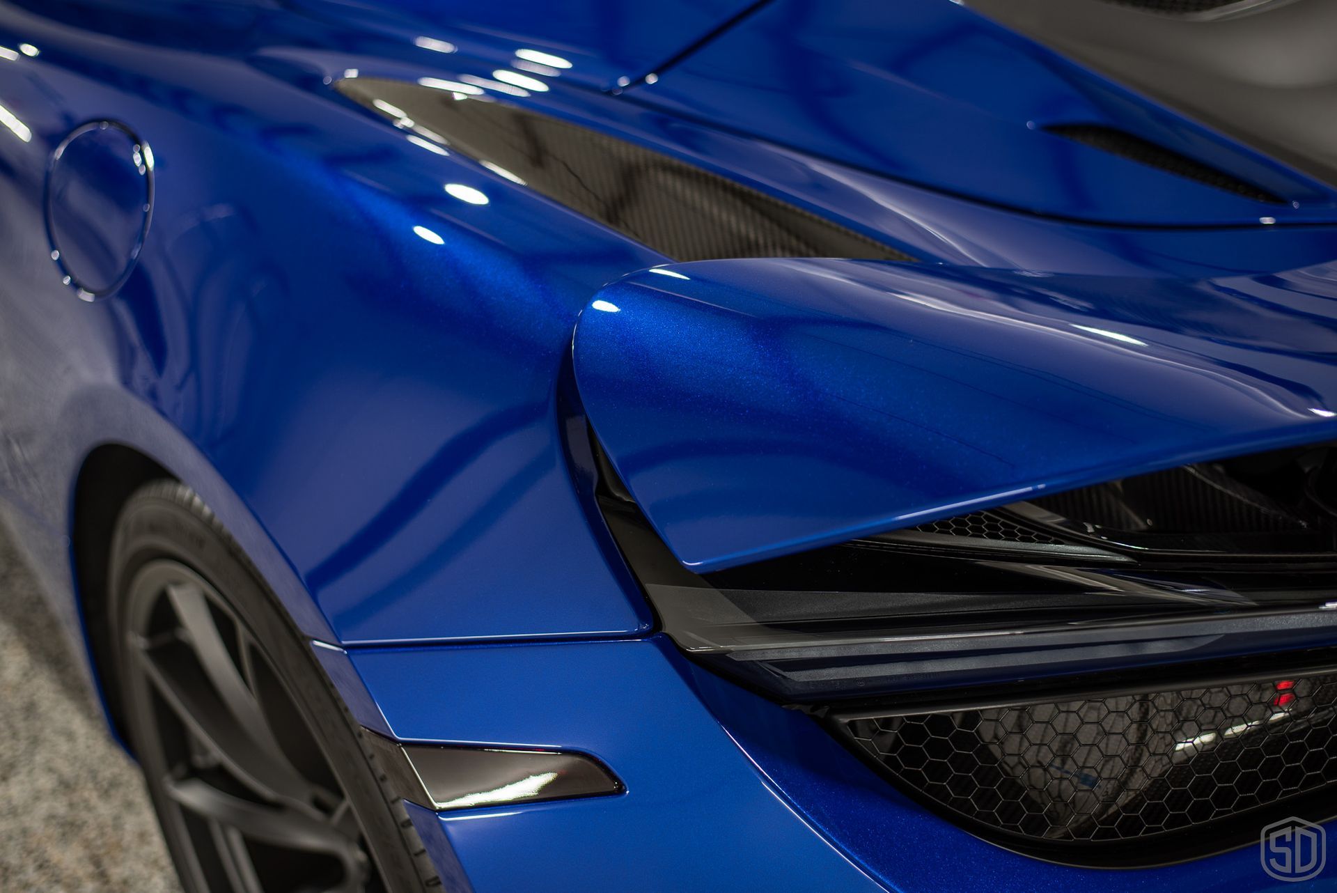 A close up of the front end of a blue sports car.