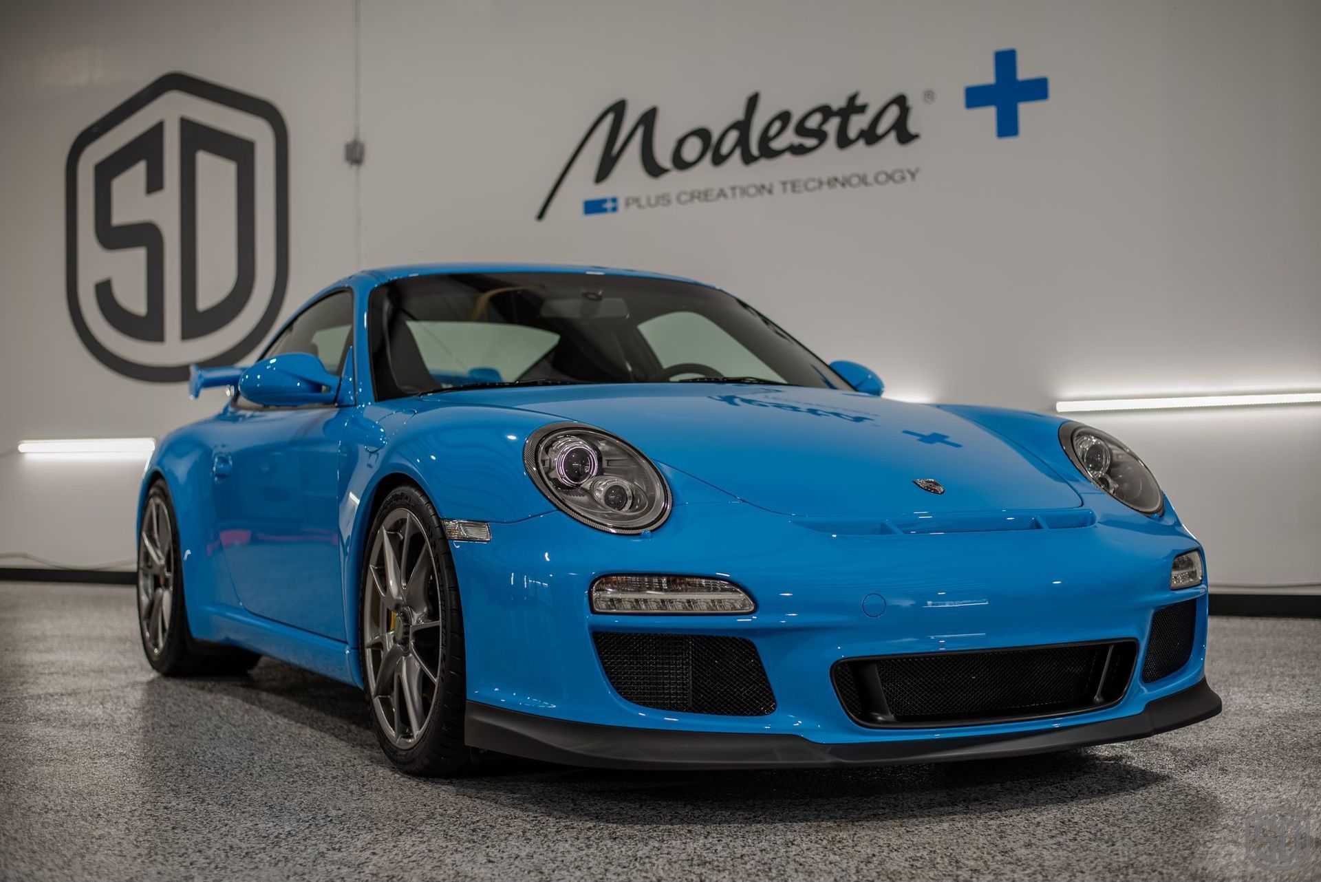 A blue porsche 911 gt3 is parked in a garage.