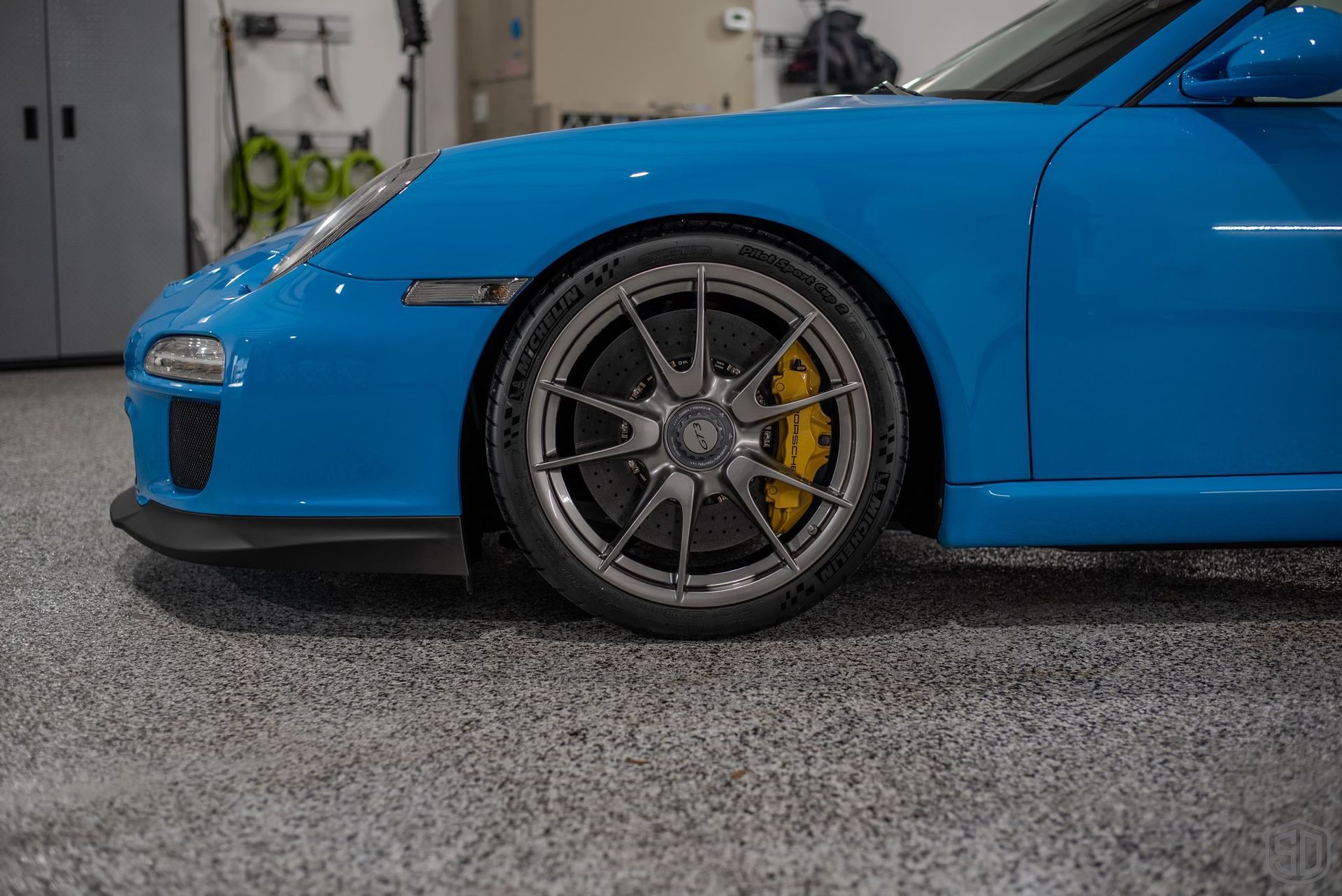 A blue porsche 911 gt3 rs is parked in a garage.