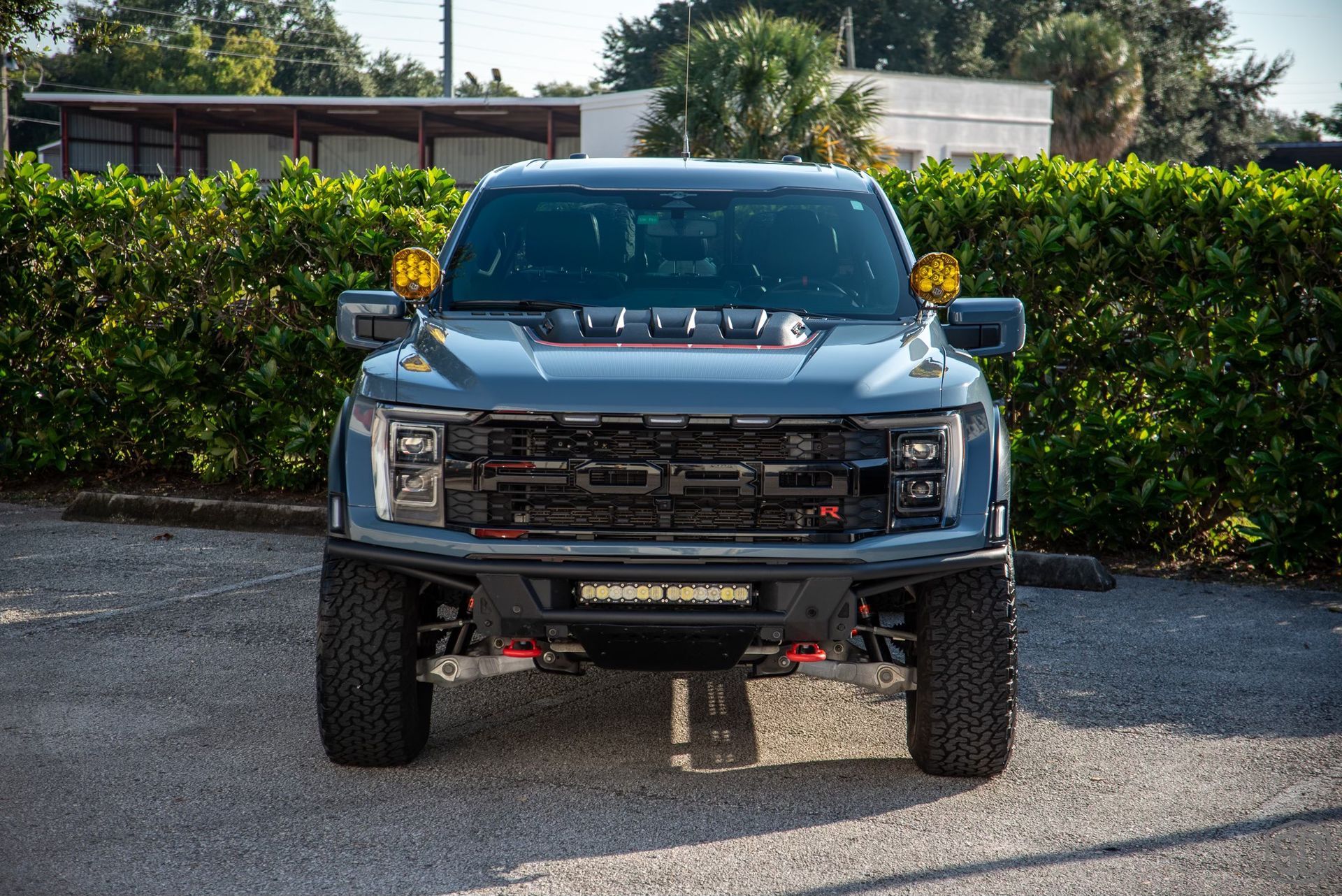 The front of a ford raptor is parked in a parking lot.