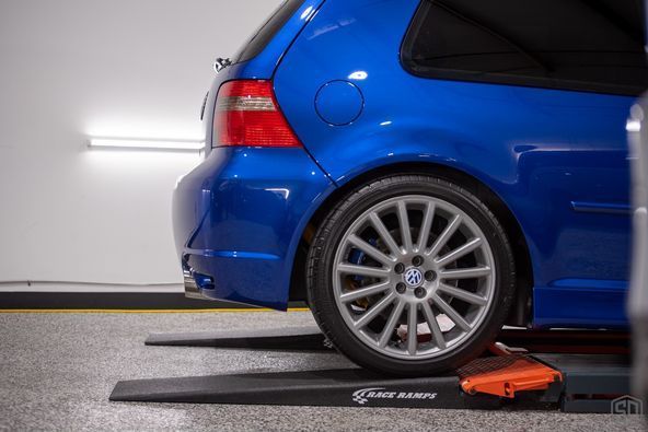 A blue car is parked on a ramp in a garage.